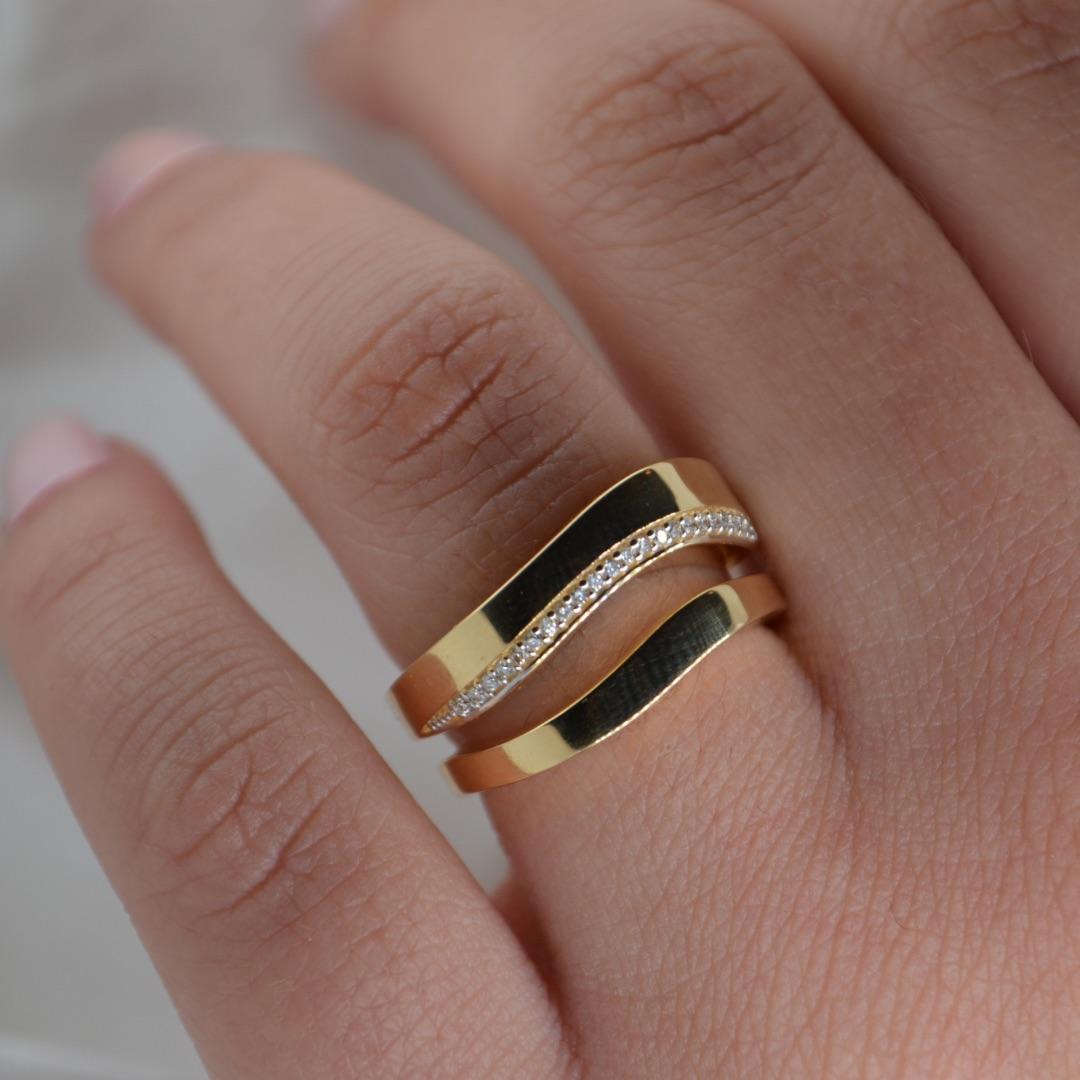 Experience timeless elegance with this 18K gold wave ring, a perfect blend of sophistication and modern design. The asymmetrical ring features two sleek bands that gracefully curve to mimic the gentle flow of waves, with one band adorned with