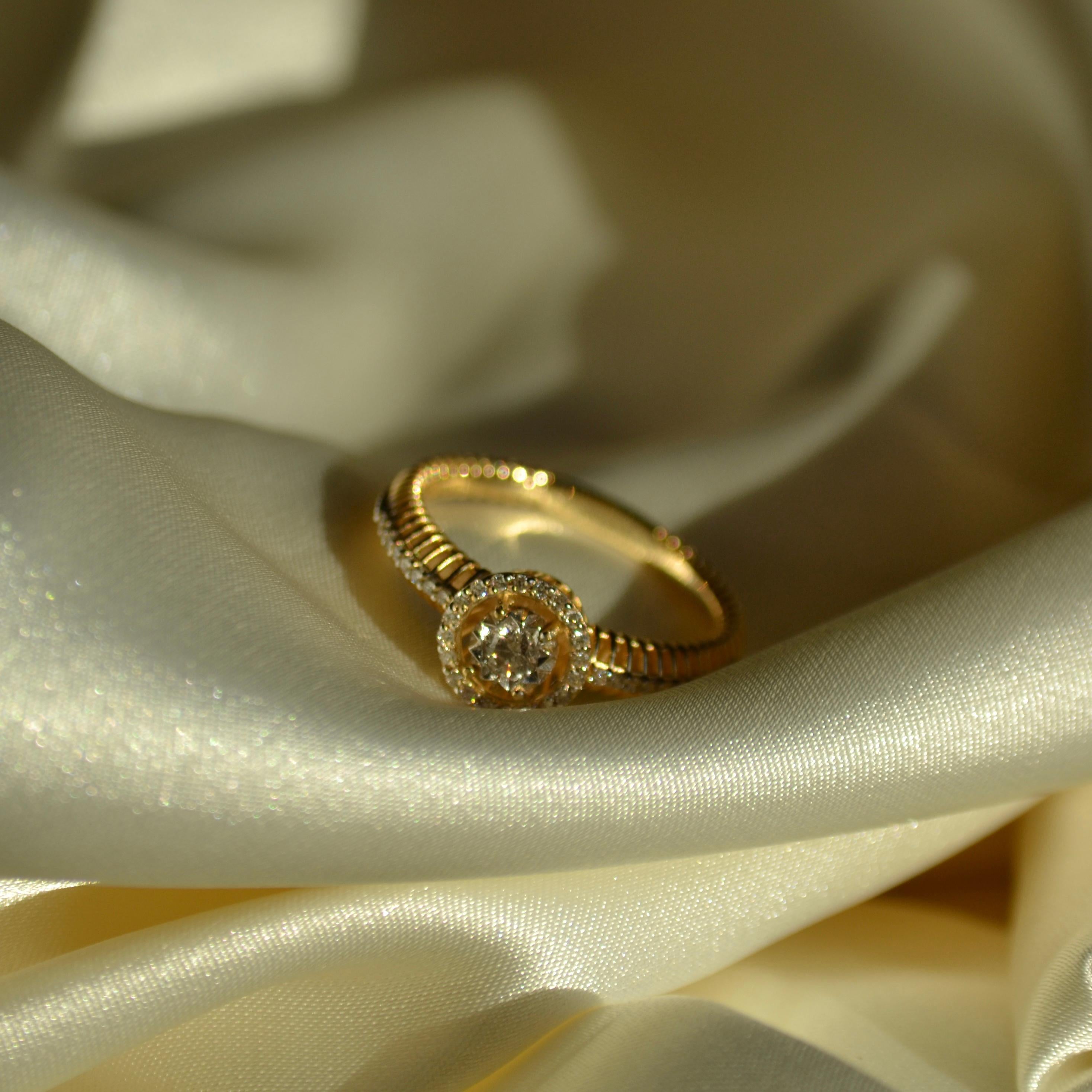 Celebra la elegancia con este exquisito anillo de compromiso de oro amarillo de 18 quilates, con un deslumbrante diamante en el centro, rodeado de un impresionante halo de diamantes más pequeños. El diseño del halo amplifica el brillo de la piedra