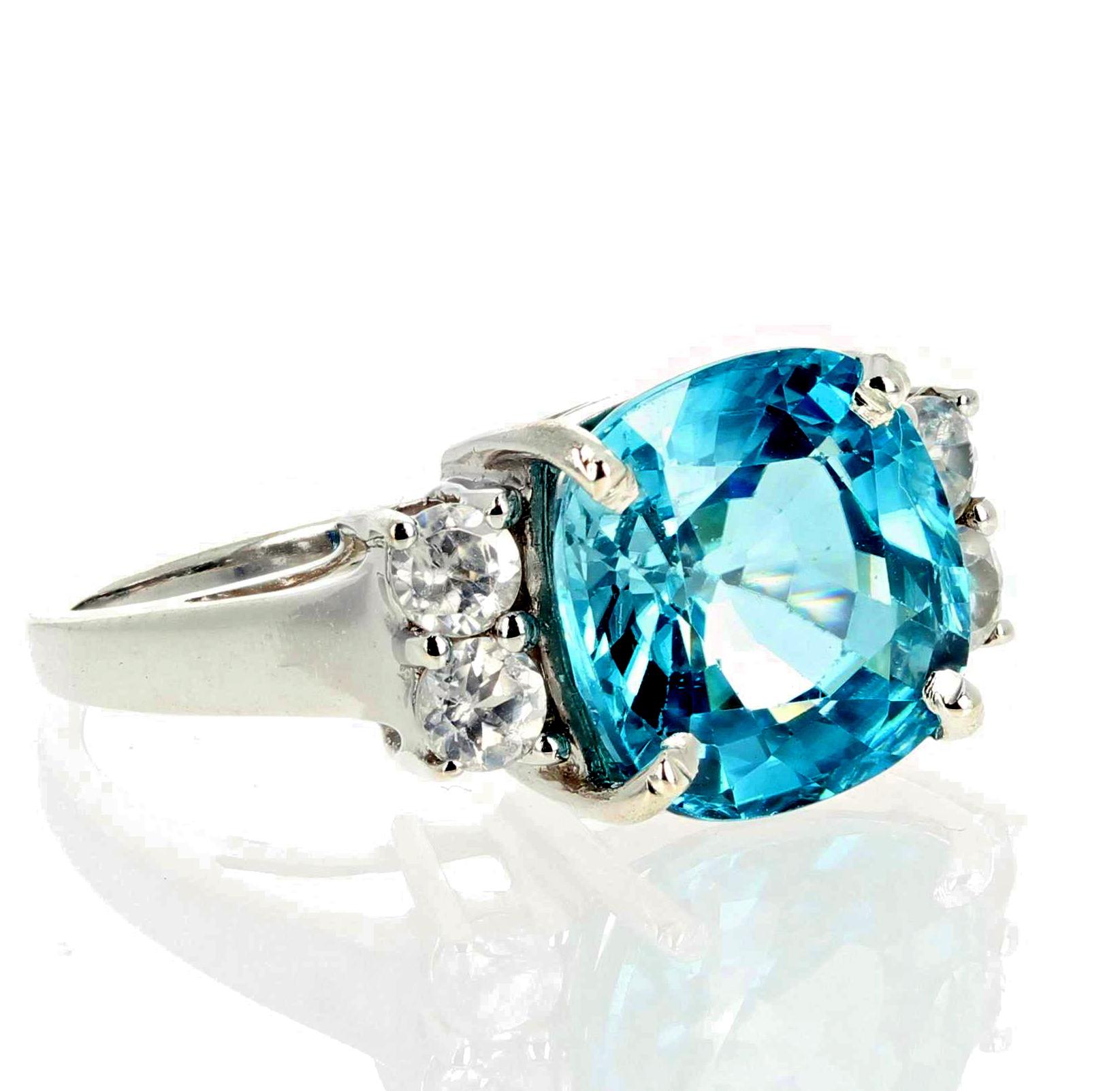 Glittering natural 6.82 carat cushion cut Blue Zircon (10.2mm x 10 mm) enhanced with smaller real white Diamonds set in a Rhodium plated sterling silver ring size 7 (sizable for free).  This is elegant for all occasions. 