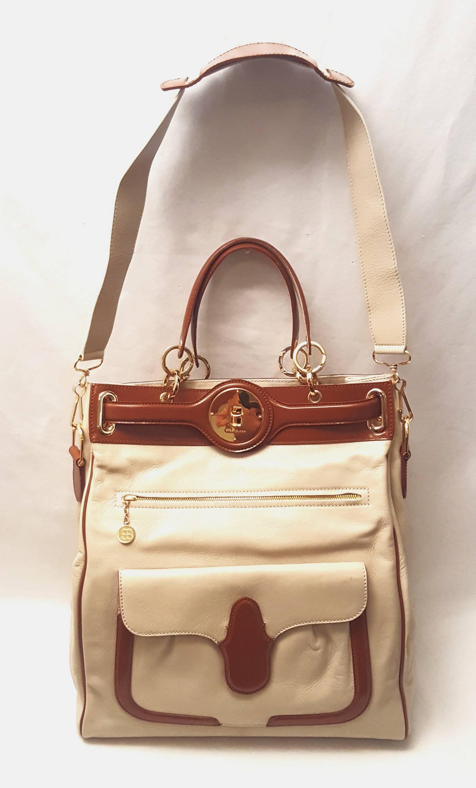 Balenciaga beige and brown from the 2008 collection with gold tone hardware travels well as a carry on or for a day excursion. This bag is lined in black canvas and contains one single large opening with one side zippered pocket.   The exterior has