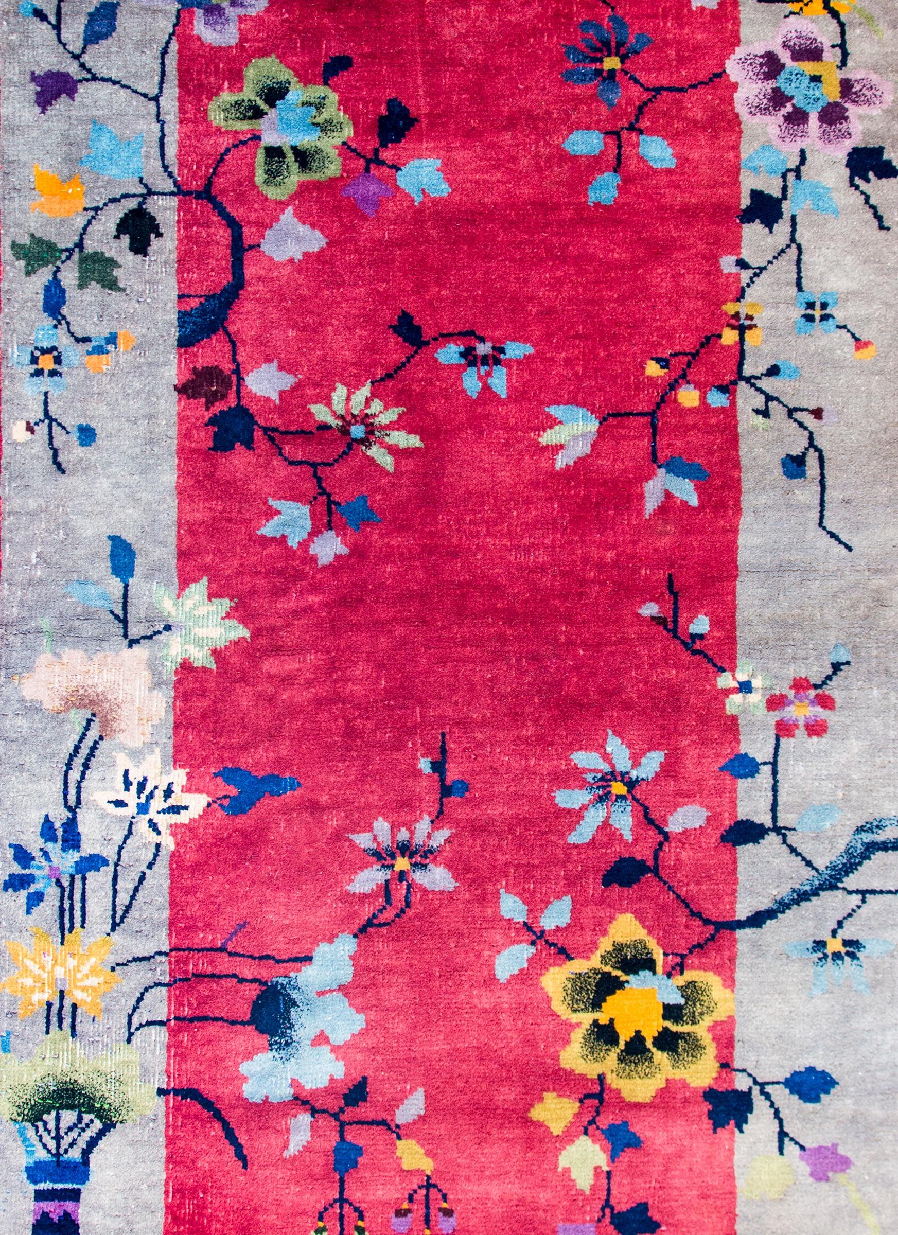 A brilliant early 20th century Chinese Art Deco rug with a bold fuchsia field surrounded by a wide grey border. Two vases, potted with flowering peonies and chrysanthemums, are positioned in opposing corners, with flowering branches scattered