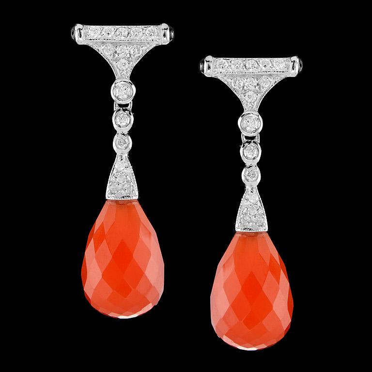 Art Deco Style Drop Earrings crafted in 9K White Gold. A pair of Brilliant Cut Carnelian drops 14.75 ct. swing below a pair of sparkling diamonds set (32 pcs. 0.35 ct.) and small onyx (4 pcs. 0.24 ct.) on the side. They are fashionable and you could