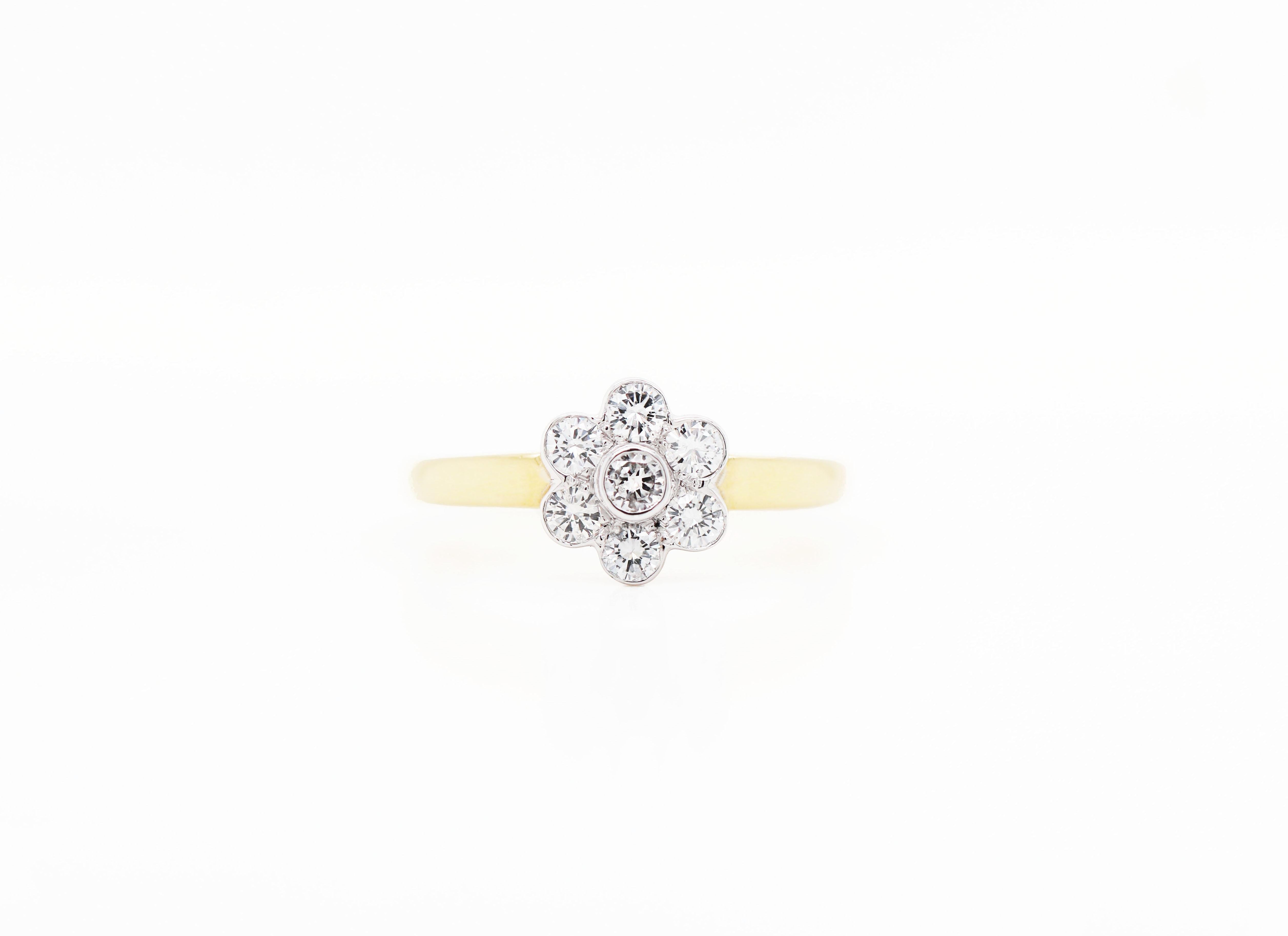 Lovely flower cluster ring set with 0.50 carat of fine quality brilliant cut diamonds in open back rub over settings. The flower is set in 18 carat white gold and sits atop an 18 carat yellow gold shank, hallmarked 750, UK finger size 'L'.



