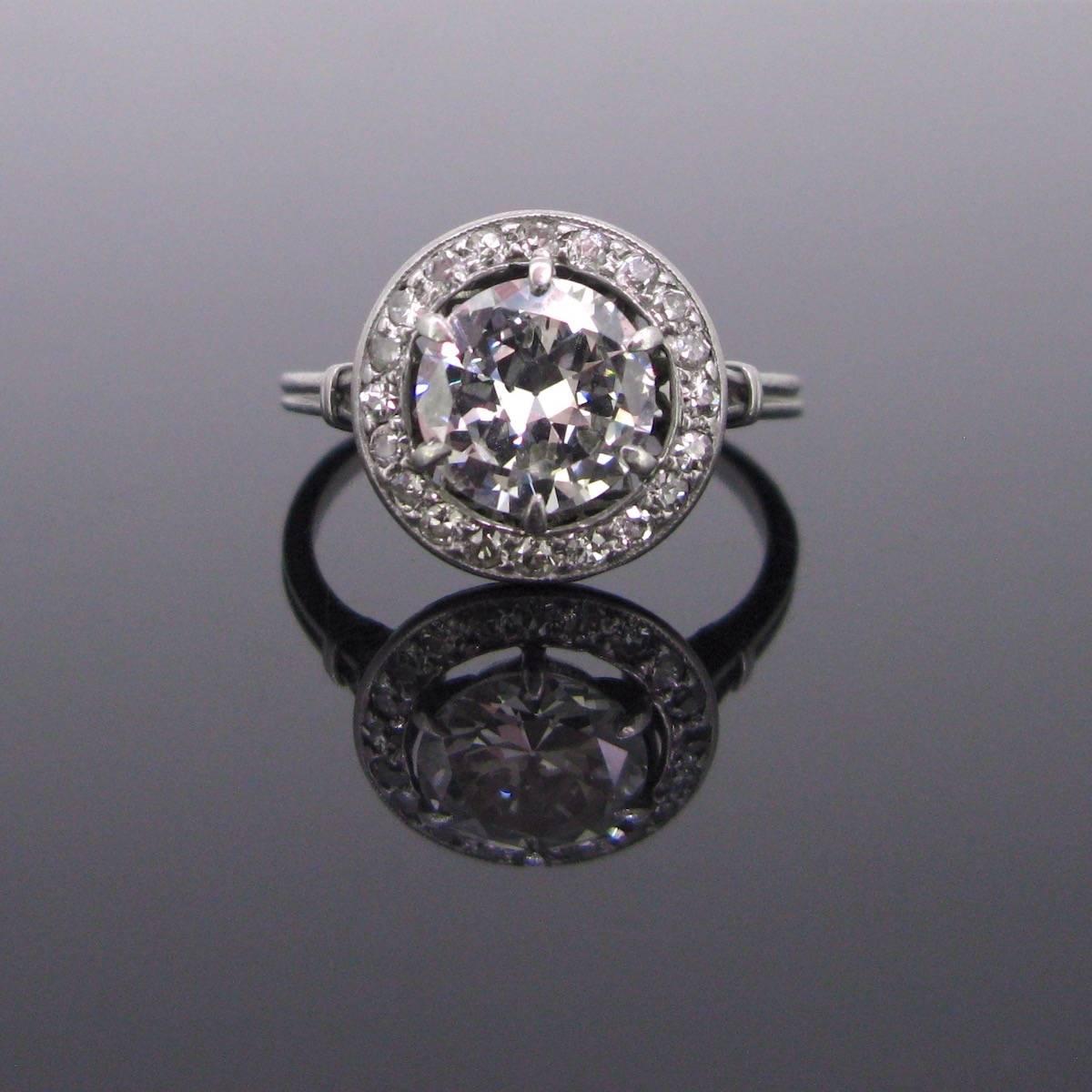 This beautiful Art Deco ring is made in platinum. It is set with a vibrant 1.80ct app diamond, graded H/I for the colour and SI2 for the clarity. It is surrounded with diamonds. The mount is airy and the corpse of the ring is very refined. It is