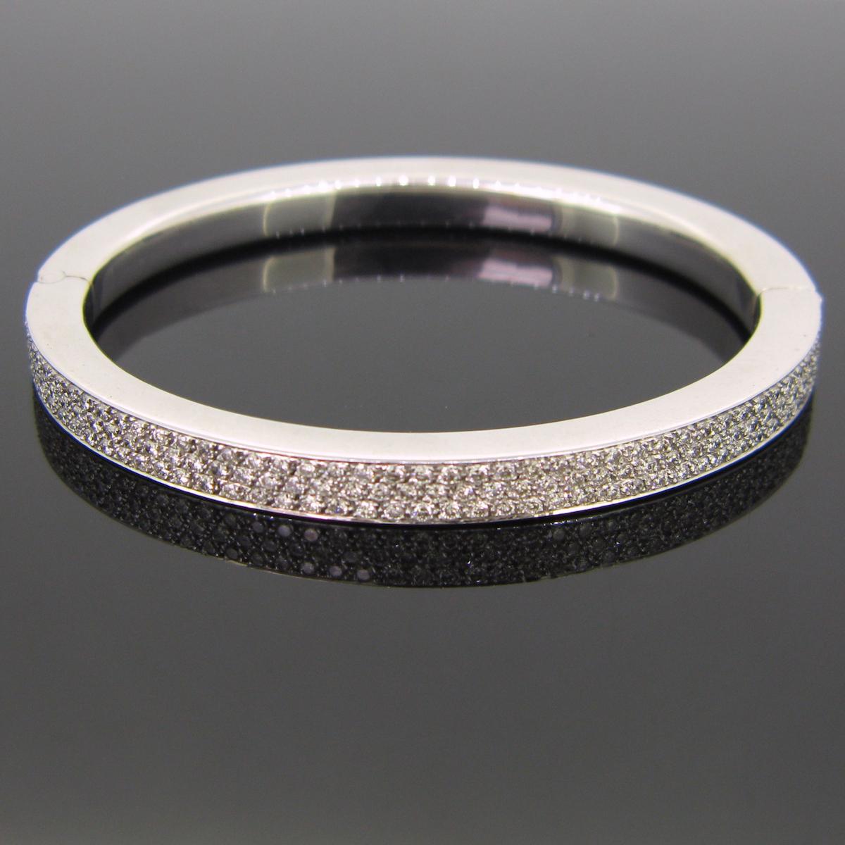 This modern bangle is made in 18kt white gold. The front is paved with 3 lines of brilliant cut diamonds with an approximate carat total weight of 4ct. The bottom part is smooth 18kt white gold.

 Weight : 35,8 gr

Dimensions : 7 cm x 6 cm

Stones :