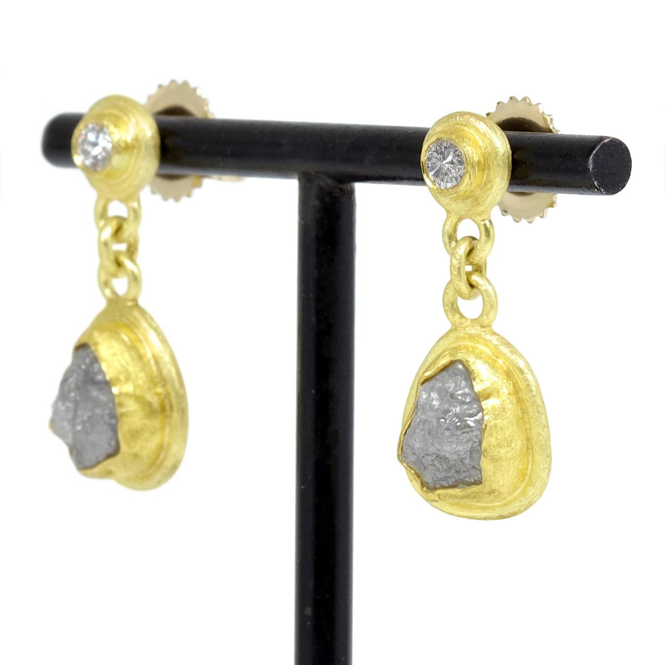 Ces boucles d'oreilles uniques à double diamant, réalisées à la main par l'artiste joaillière primée Petra Class, sont composées d'un diamant taille brillant serti en chaton et d'un diamant brut enveloppé et encadré individuellement dans de l'or