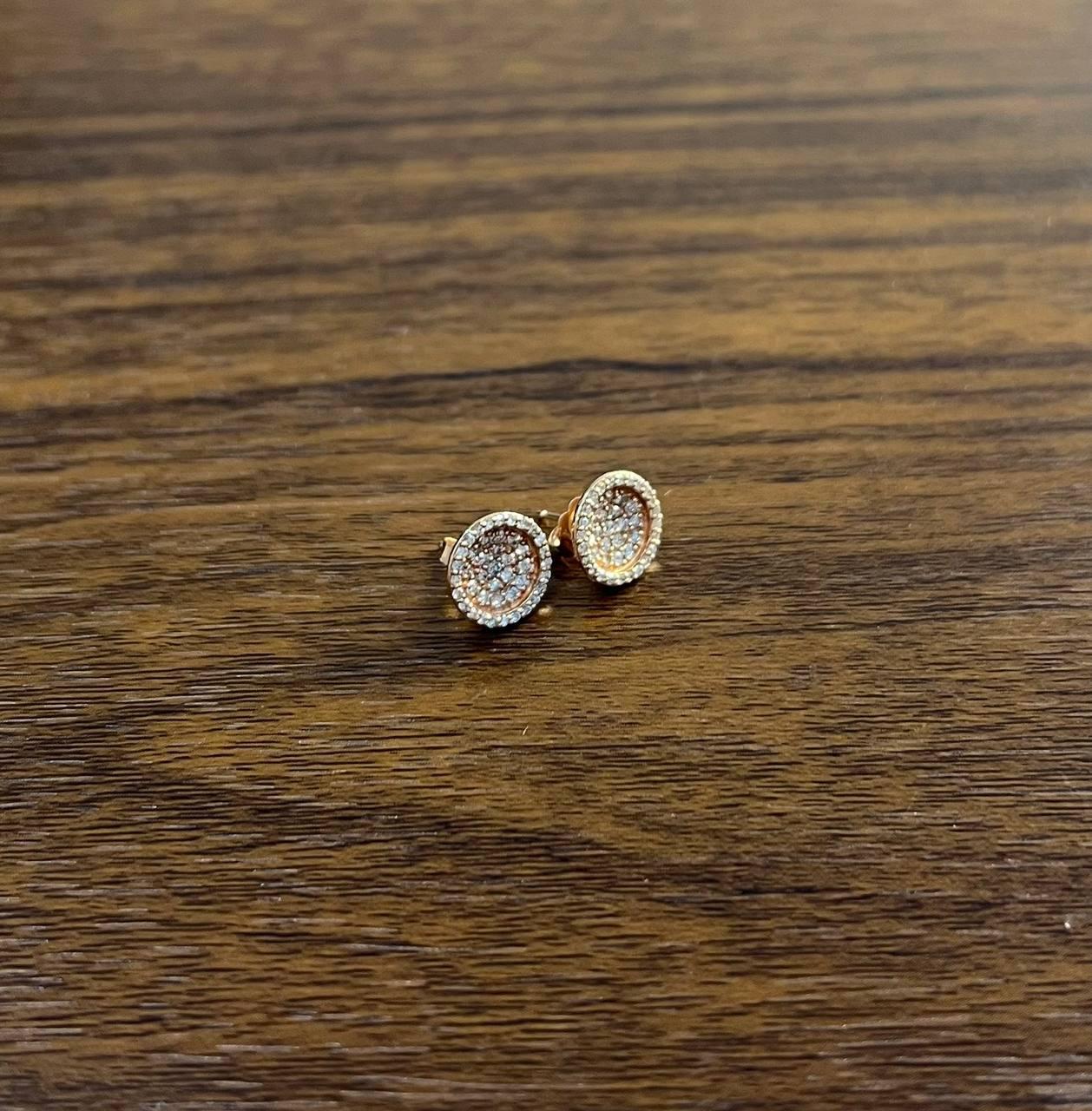 These elegant earrings feature a circular design encrusted with sparkling diamonds. The intricate arrangement of stones creates a dazzling effect, enhancing the overall brilliance. 14K Rose Gold. 0.57 CTW Diamonds