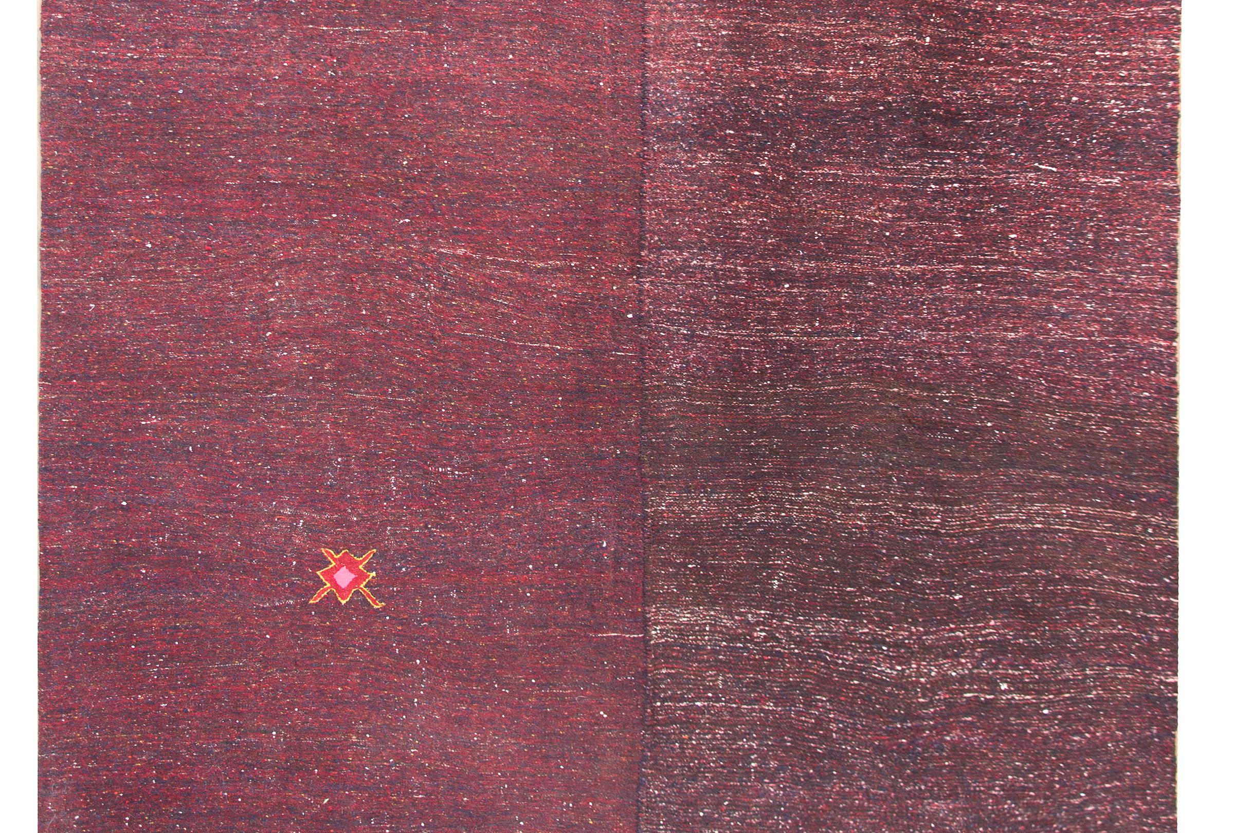 A simple but chic mid-20th century Persian Gabbeh kilim rug woven in crimson and indigo wool with a wonderful stylized flower and simple whip stitched edge trim.  Composed of two panels stitched together.