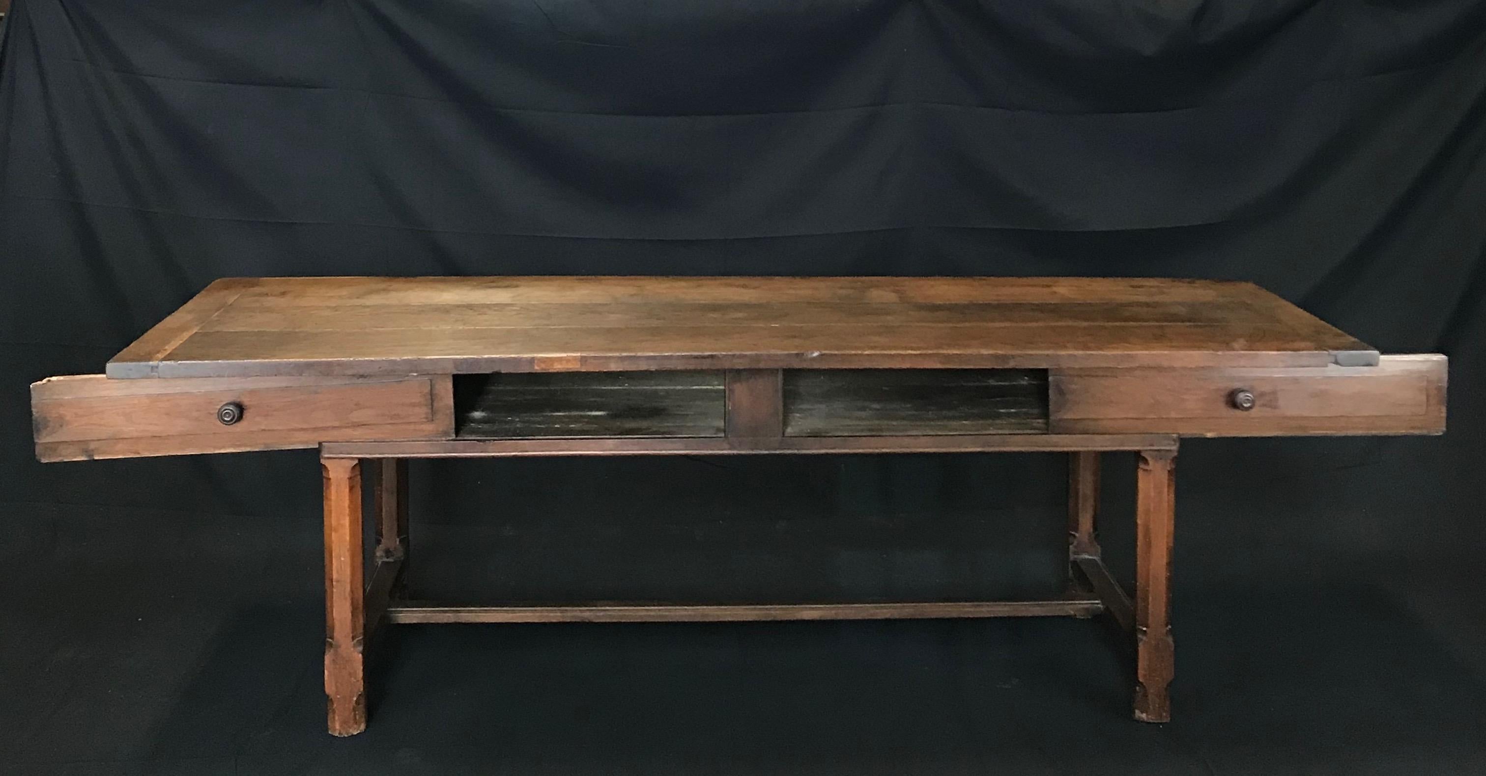 A spectacularly aged oak farmhouse table from the French countryside near Lyon, made around the early 1800s. The table has a marvelous top of three boards with canted corners and breadboard ends. Two large sliding drawers reside in the table’s