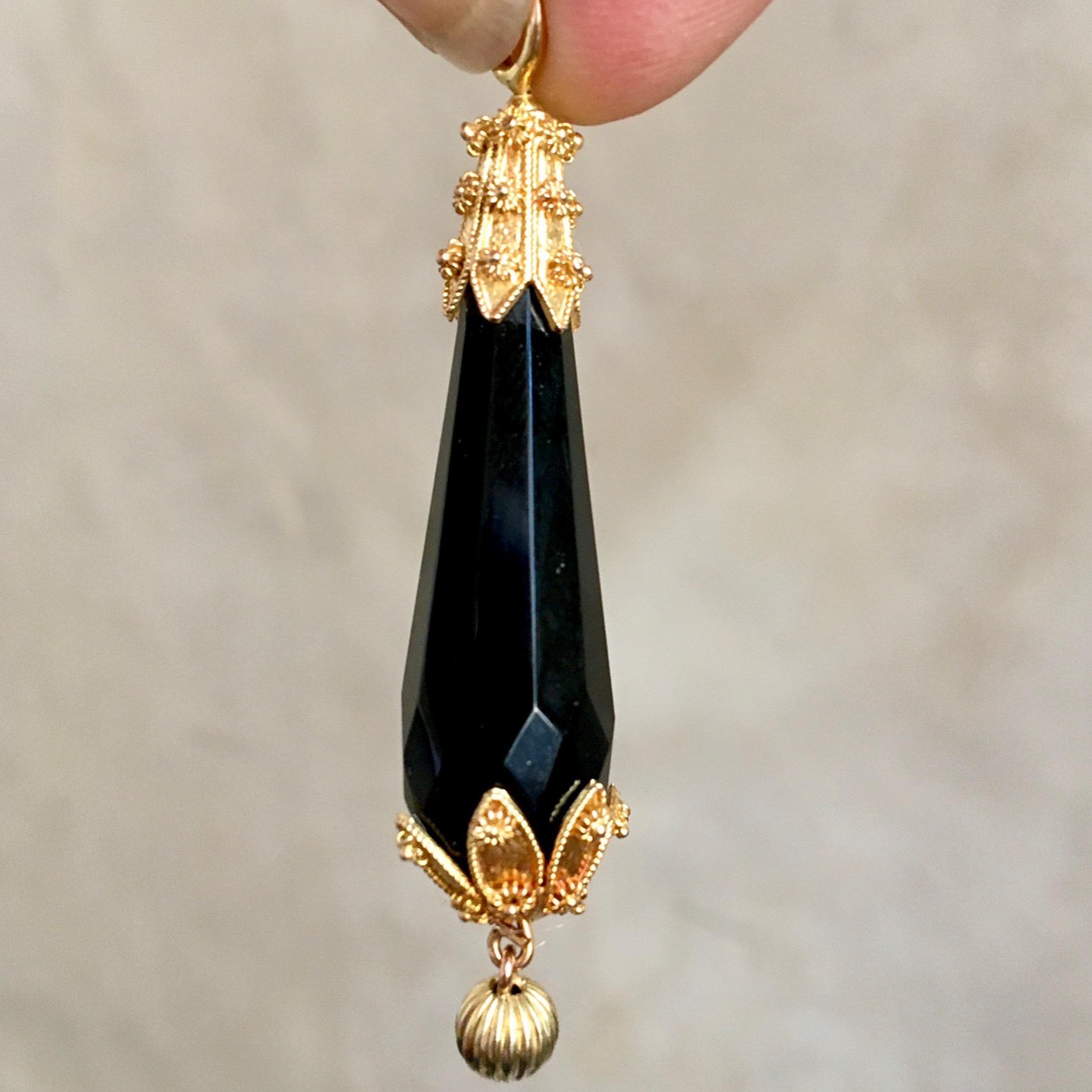 An early 20th century faceted black jet briolette cannetille pendant. This pendant is created with 14 karat gold cannetille work caps at the top and bottom. The top and bottom of the pendant is adorned with spider-like rosette ornaments and groove