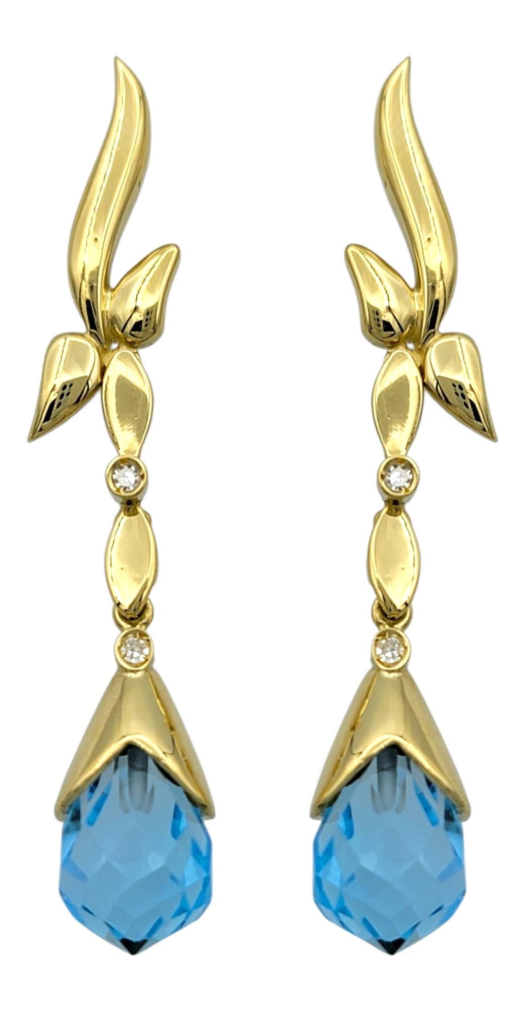 These enchanting designer-cut blue topaz earrings dazzle with bold elegance and vibrant charm. Each earring features a brilliantly faceted blue topaz that radiates rich color, secured in warm 18 karat yellow gold for a luxurious contrast. Small