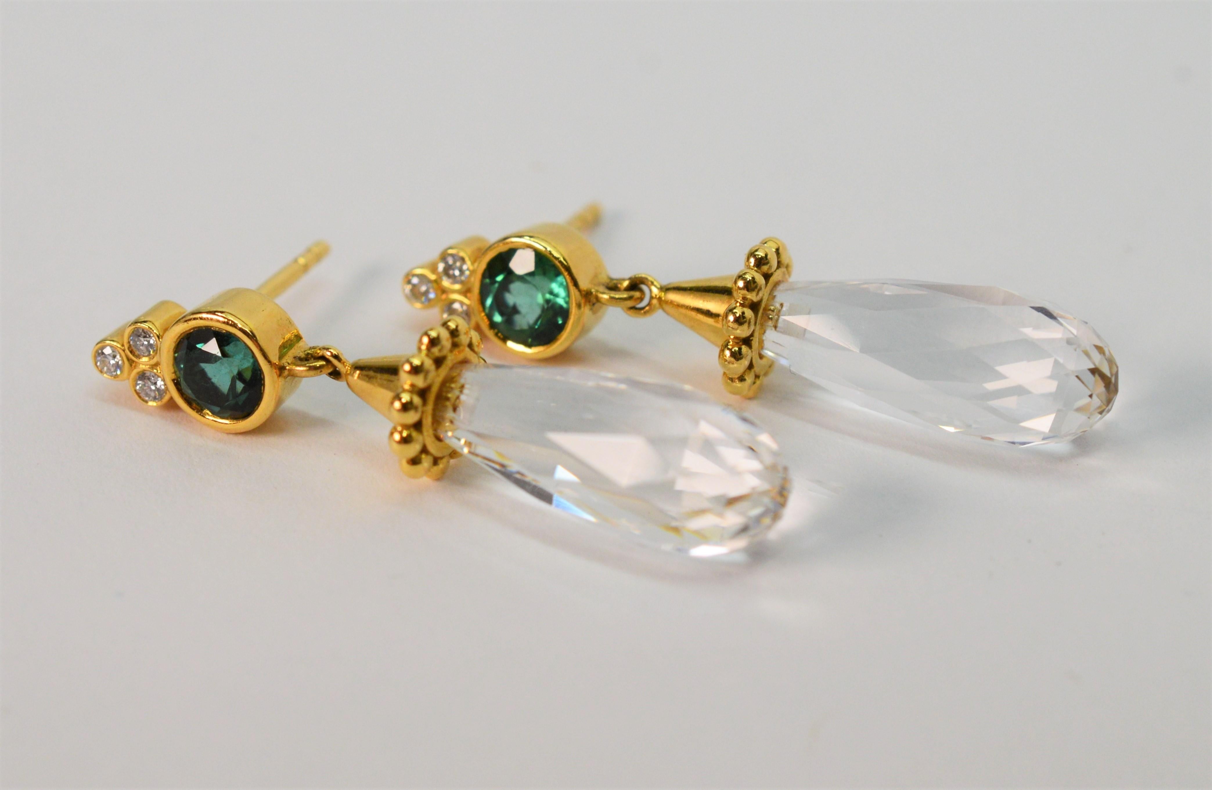 Stunning briolette rock crystal teardrops catch light and shimmer as they dangle from fancy trumpeted eighteen karat 18K yellow gold findings. A bezel set .40 carat faceted emerald with .03 carat H/VS diamond accents divinely adorn each stud