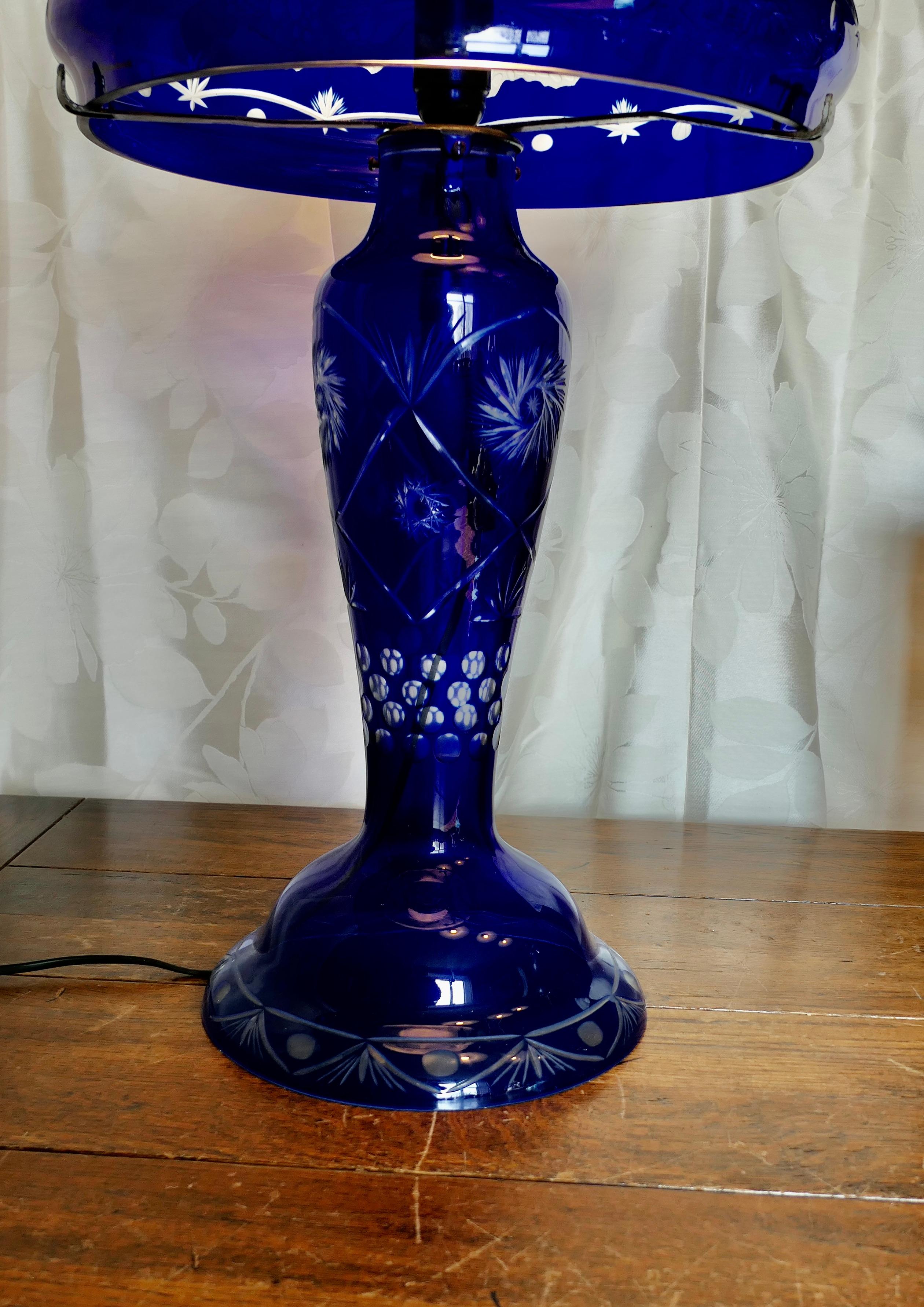 Lampe Bristol bleu cobalt avec abat-jour en verre

La base de la lampe a une forme de vase et est mise en valeur par un abat-jour en forme de champignon décoré de grands papillons, profondément sculptés dans le verre.
Tout le câblage est neuf, la