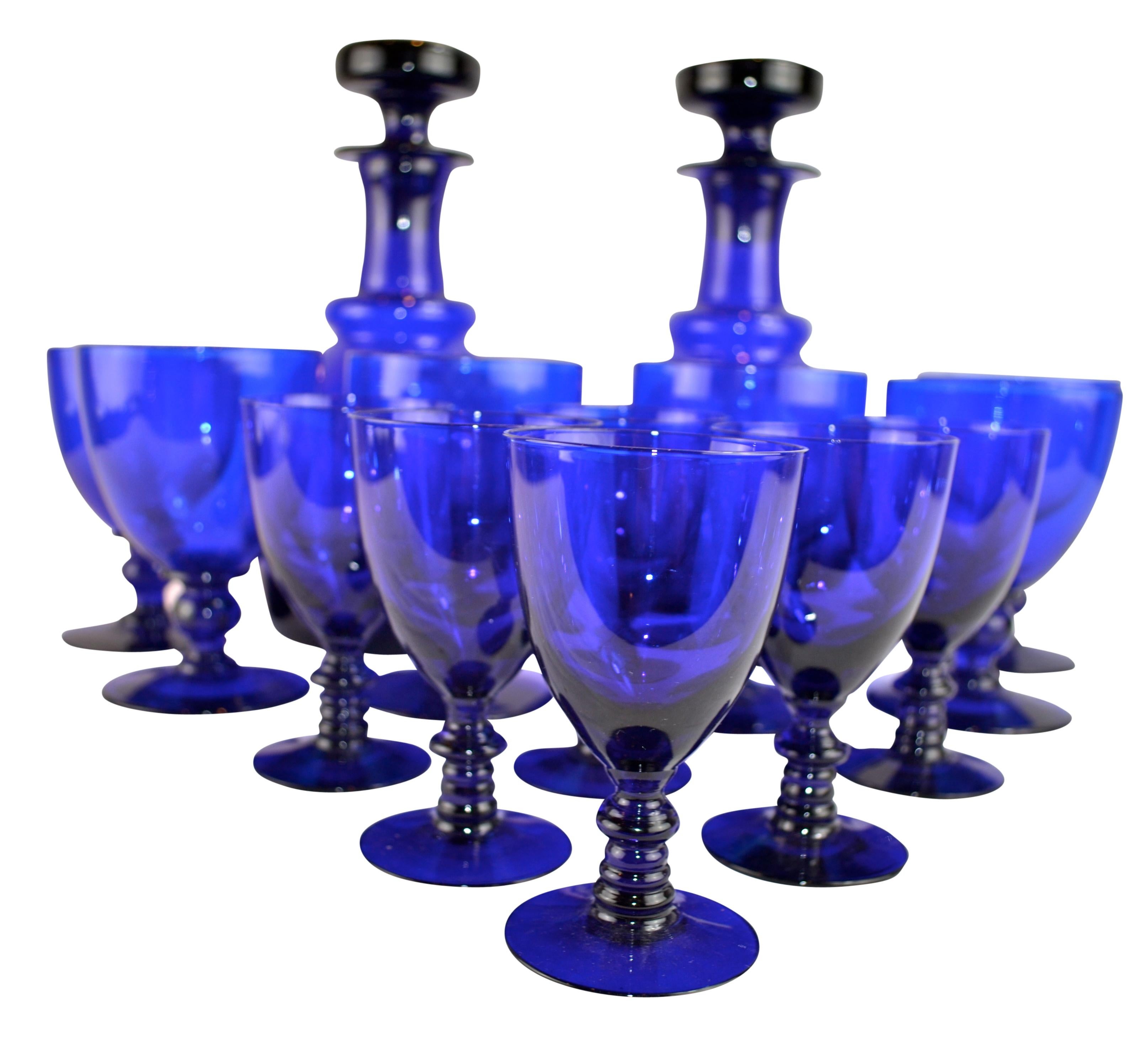 A 19th century English set of glassware in cobalt blue glass comprising two lidded decanters, six water/wine glasses, and six smaller sherry glasses, (no damage). England, circa 1840.