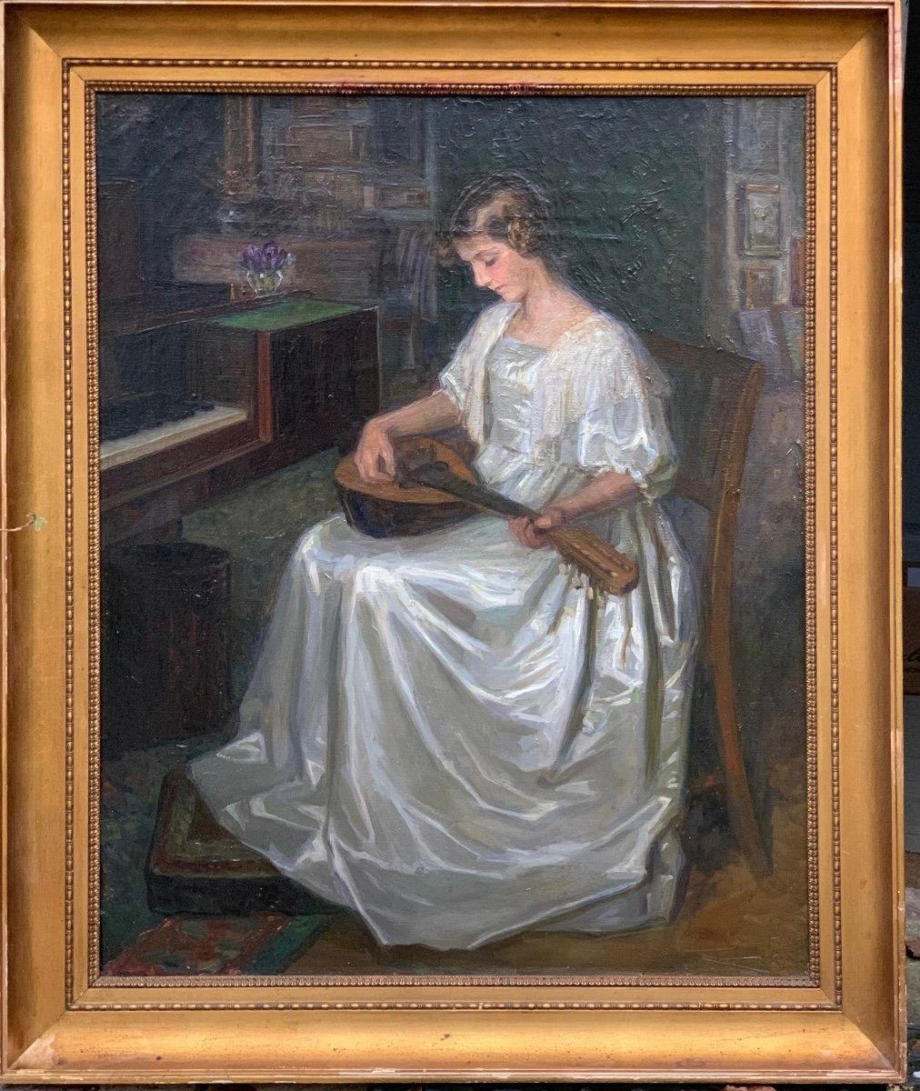 Young Mandolin Player. Signed with the BB monogram and dated 1913. Oil on canvas. 67 × 54 cm. In an interior rich of paintings and music, a very young girl applies herself to the mandolin. This scene of great sweetness is the work  work of a woman