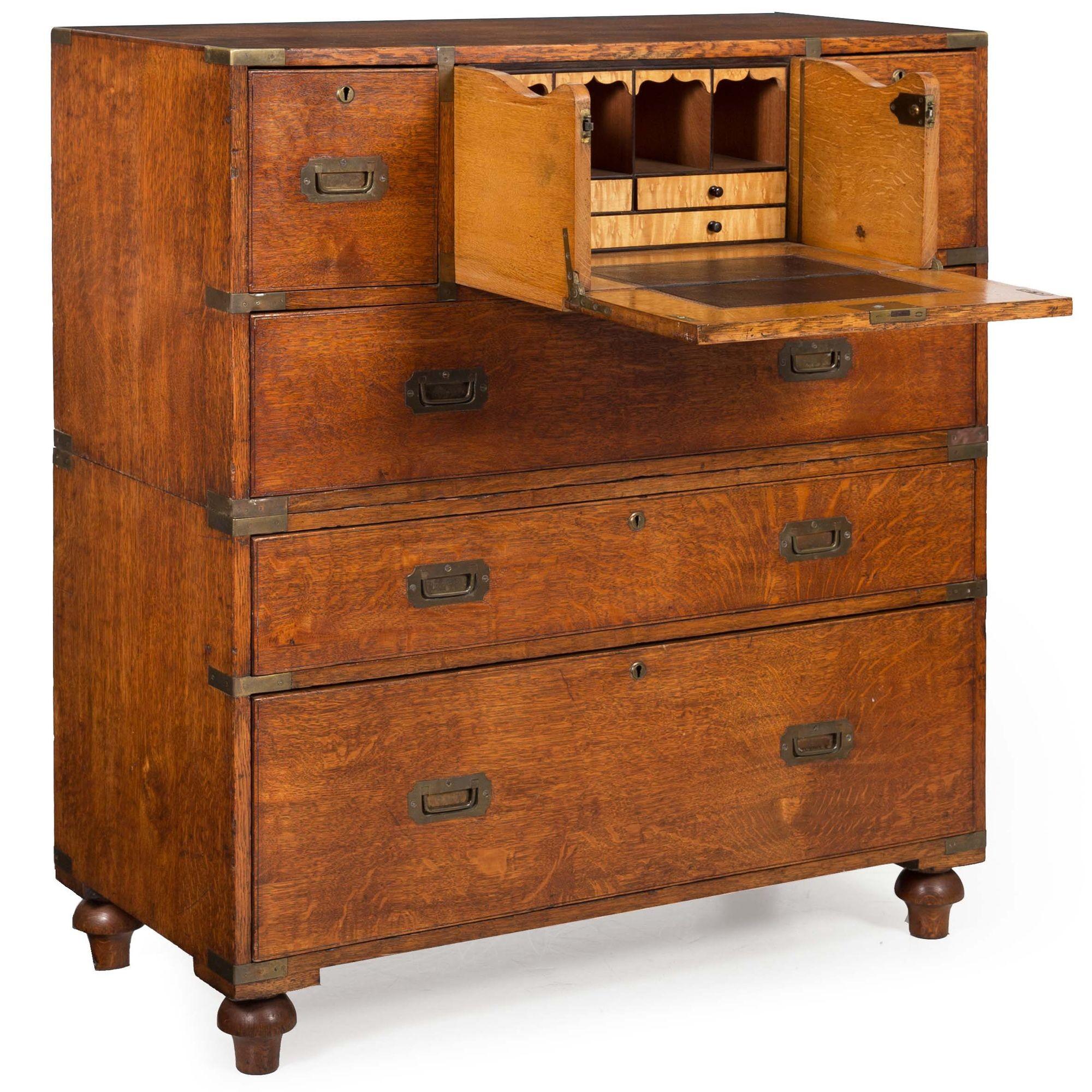 An exquisite mid-19th century British campaign chest crafted in two self-contained parts with a desk hidden inside of one of the upper drawers, it features a solid golden-oak primary wood with a silky patina throughout. Entirely pure with only a few