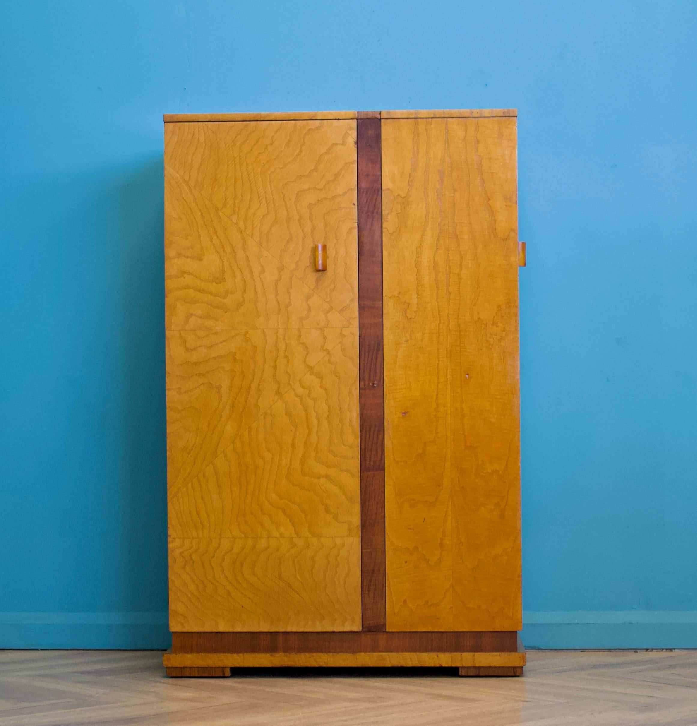 Un bellissimo esemplare di Art Deco degli anni '30 in acero e noce.  guardaroba compatto
Caratterizzato da un design unico: uno scomparto sul davanti,  con un appendino all'interno 
A lato c'è un altro scomparto, con un ripiano e dei cassetti.