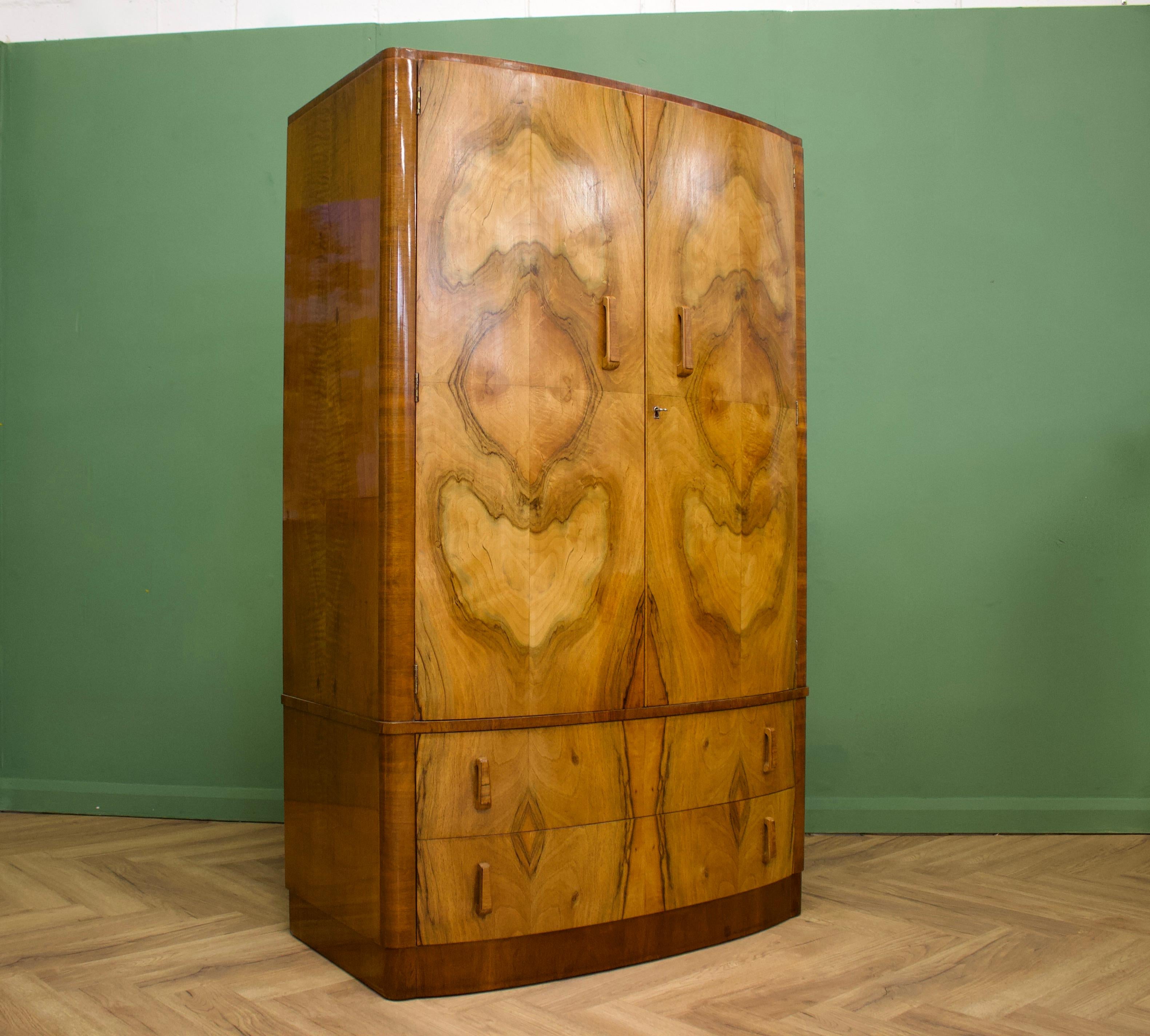 - Art Deco bow fronted wardrobe.
- Manufactured in the UK.
- Made from solid oak and burr walnut veneers.
- Internally there is a hanging rail, shelves and two glass fronted drawers
- An additional two drawers to the bottom.