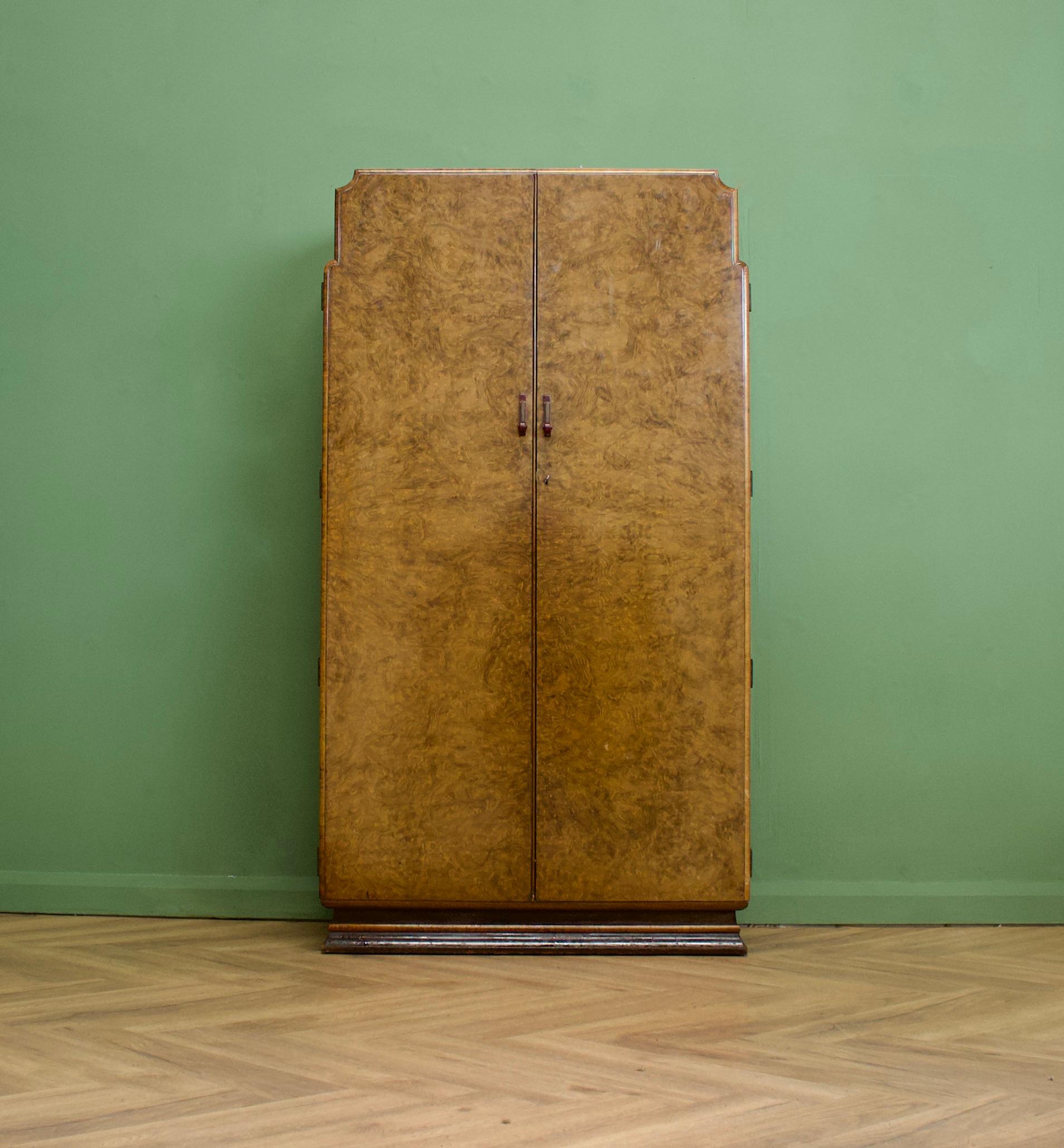 An Art Deco walnut compact wardrobe featuring a skyscraper style front
Complete with unique red bakelite and brass handles  - circa 1930's
Fitted out with a clothes and shoe rail