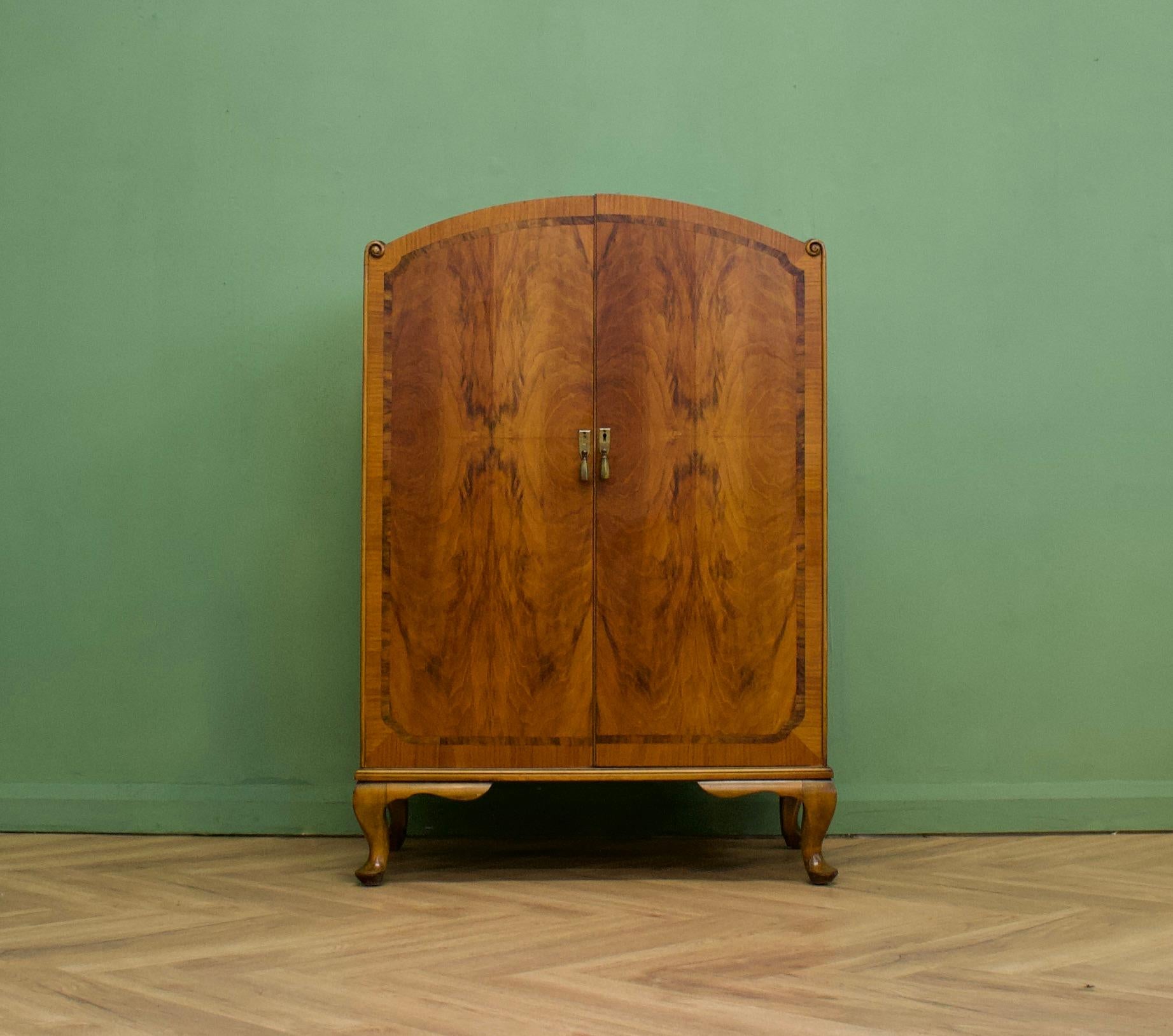 Une impressionnante armoire à linge en ronce de noyer surmontée d'un dôme, datant des années 1930. Elle comporte une étagère et des tiroirs internes. Son style et sa qualité sont très similaires à ceux de Waring et Gillow.