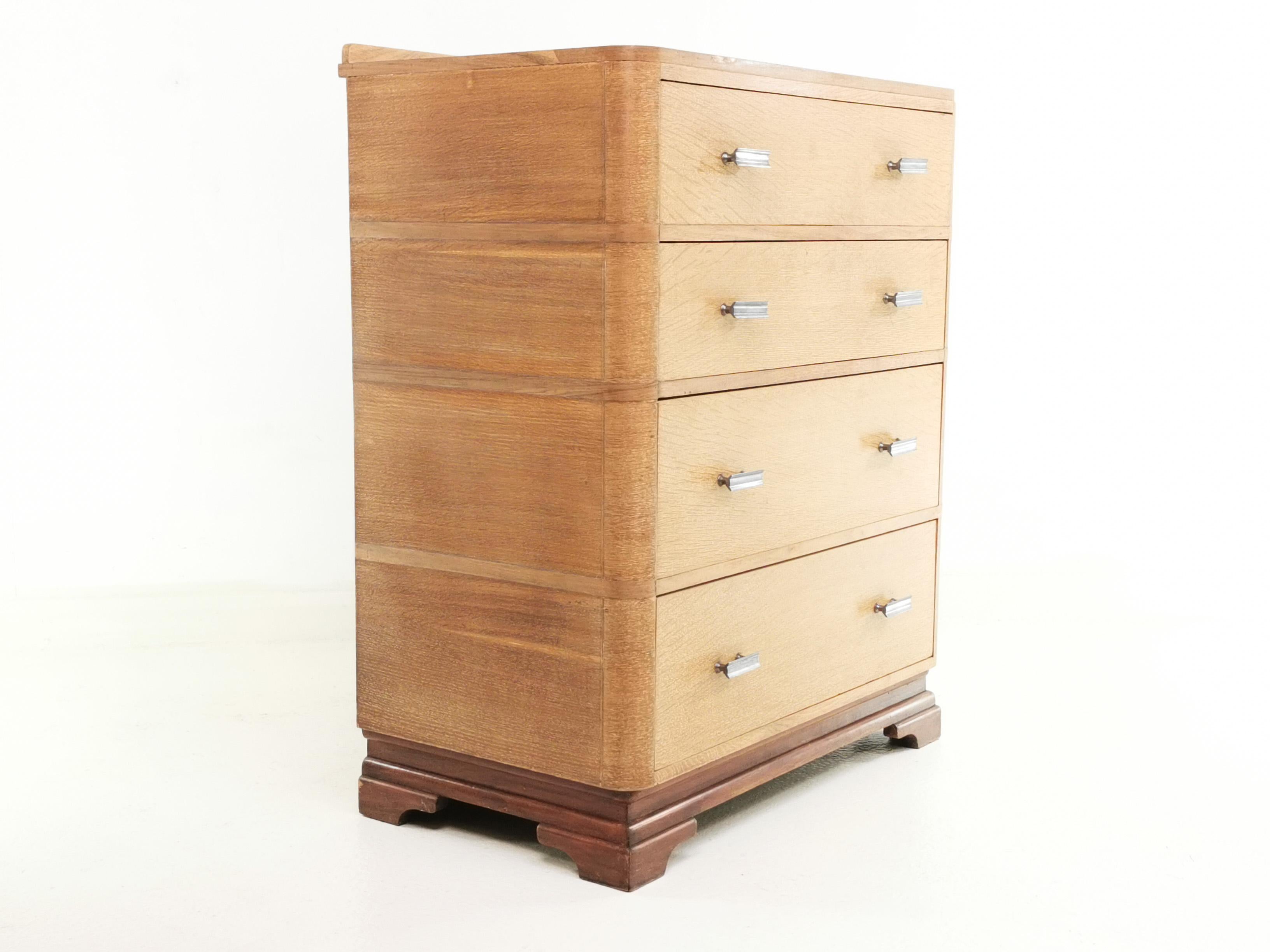 Art Deco chest of drawers 

A British early 20th century Art Deco - 1930s limed oak pedestal chest of drawers with a raised back panel over a curved bank of four deep-set and spacious drawers, each with angular metal period pulls raised on bracket