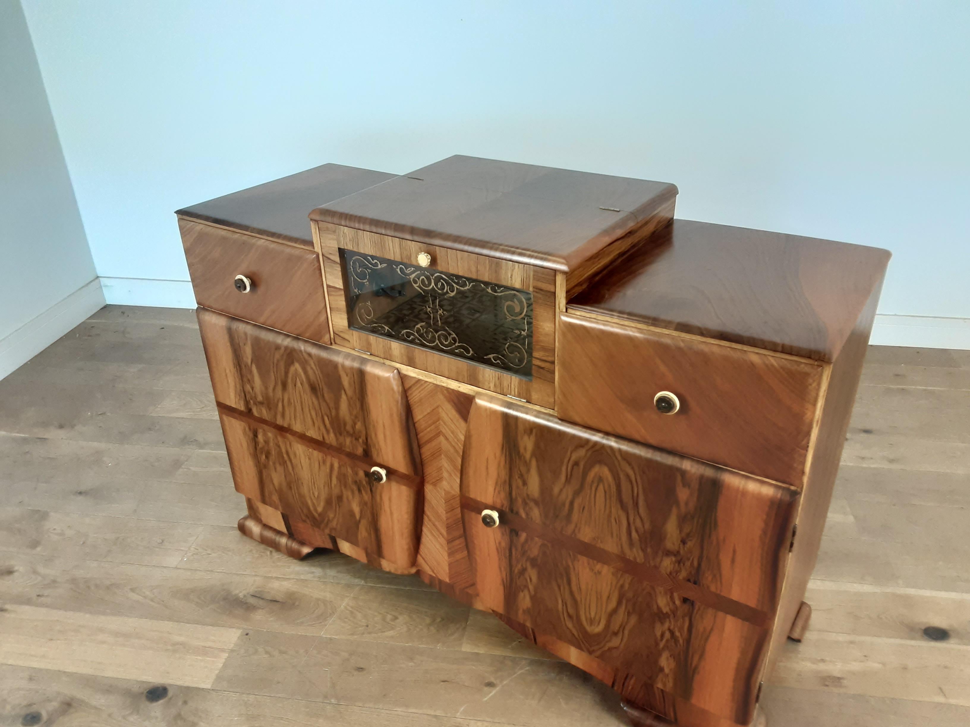 Art Deco cocktail bar.
An Art Deco cocktail sideboard with glazed fall front cocktail compartment between two drawers, the lower section with through shelving.
finished in a stunning figured walnut.
Measures: 94 cm H in the centre, 88 cm h at the