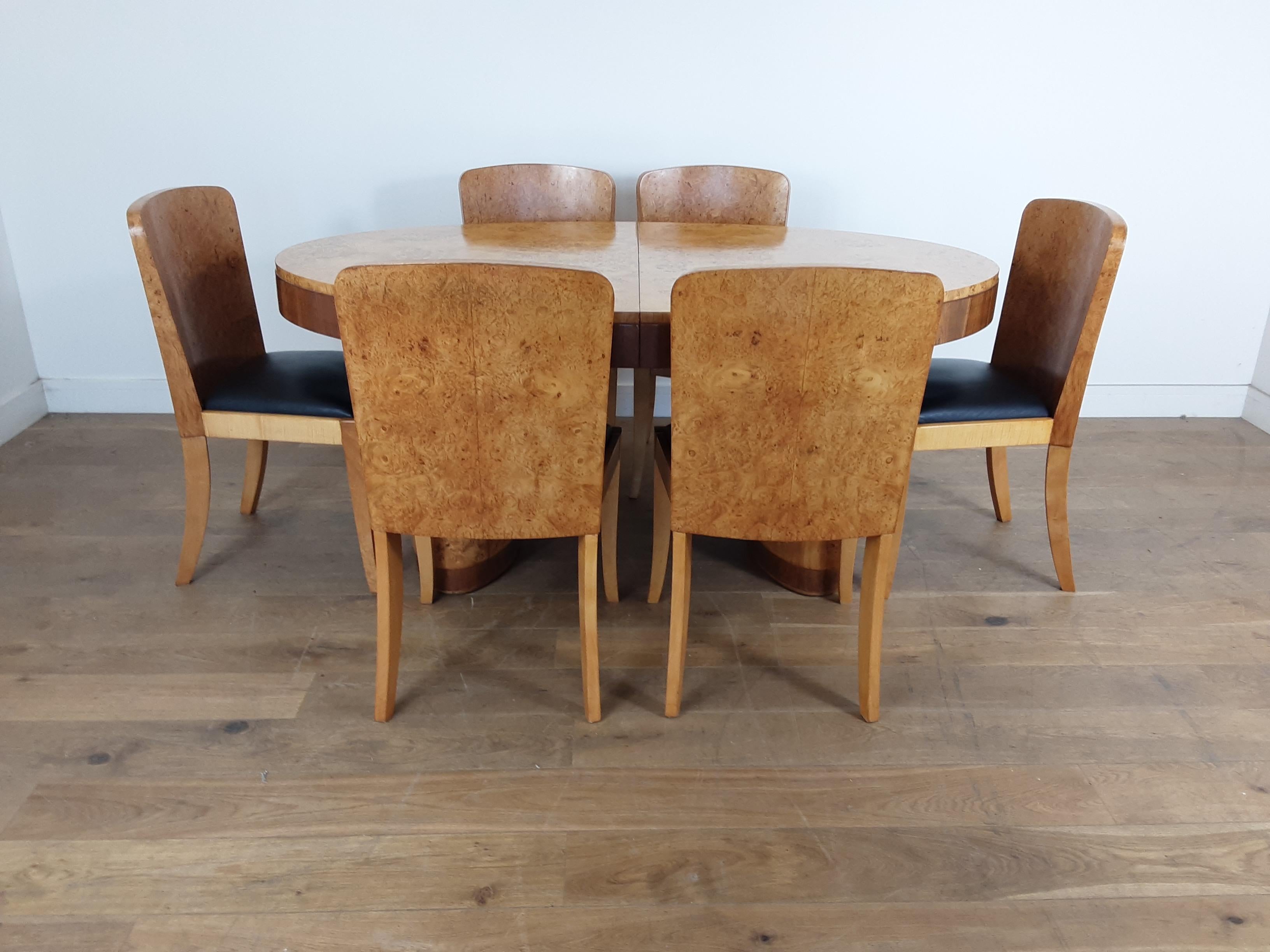 An oval Art Deco extendable dining table raised on two oval pedestals all in a stunning blond bird's-eye maple with walnut trims.
With six dining chairs in bird's-eye maple and black leather seats.
We also have glass tops for this table, two half