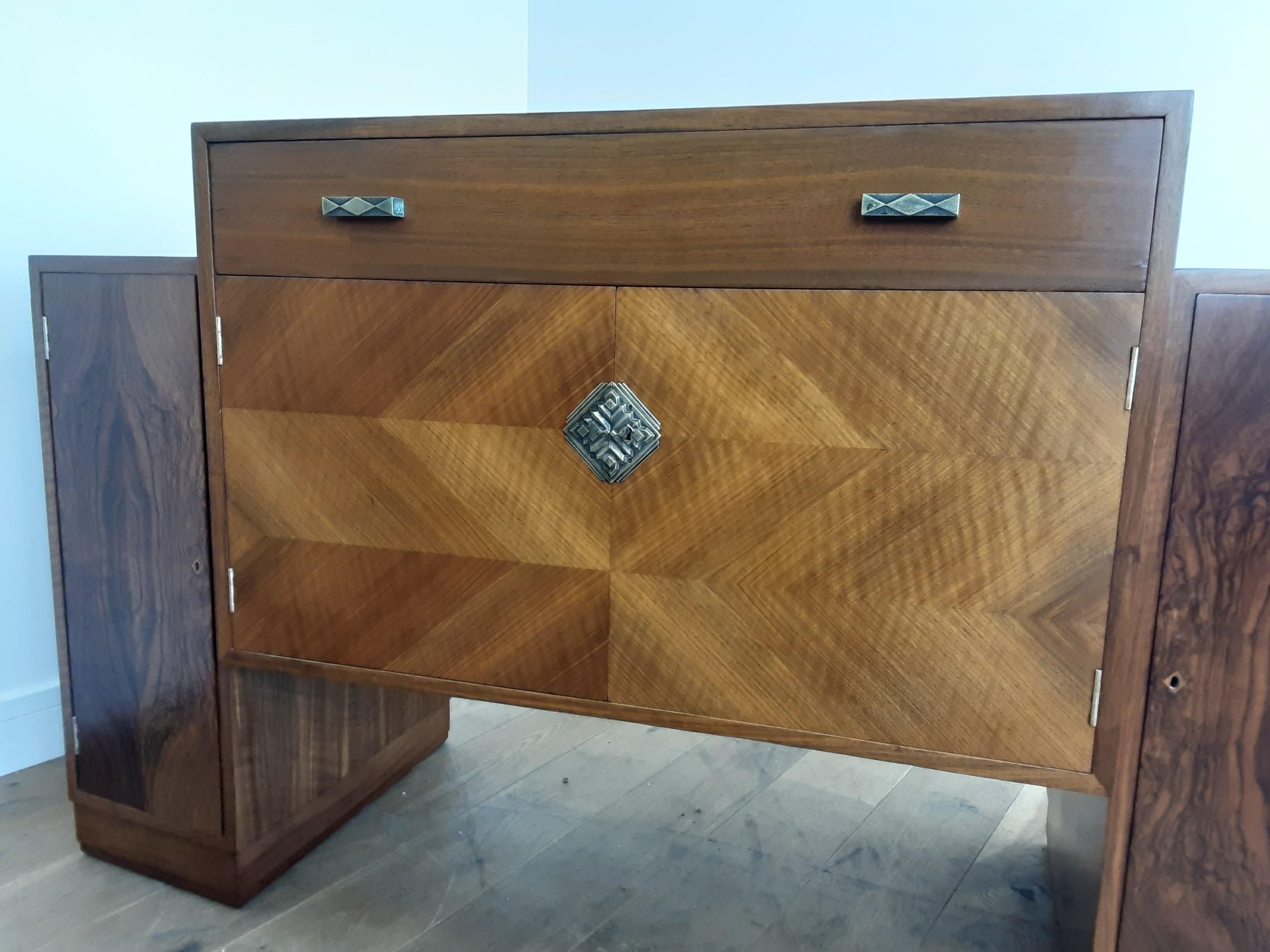 British Art Deco sideboard credenza
beautiful figured walnut side cupboards with single shelf.
The centre section with diamond metal plate and radiating diamond cut walnut veneer. shelved cupboard under single fitted drawer.
A very impressive