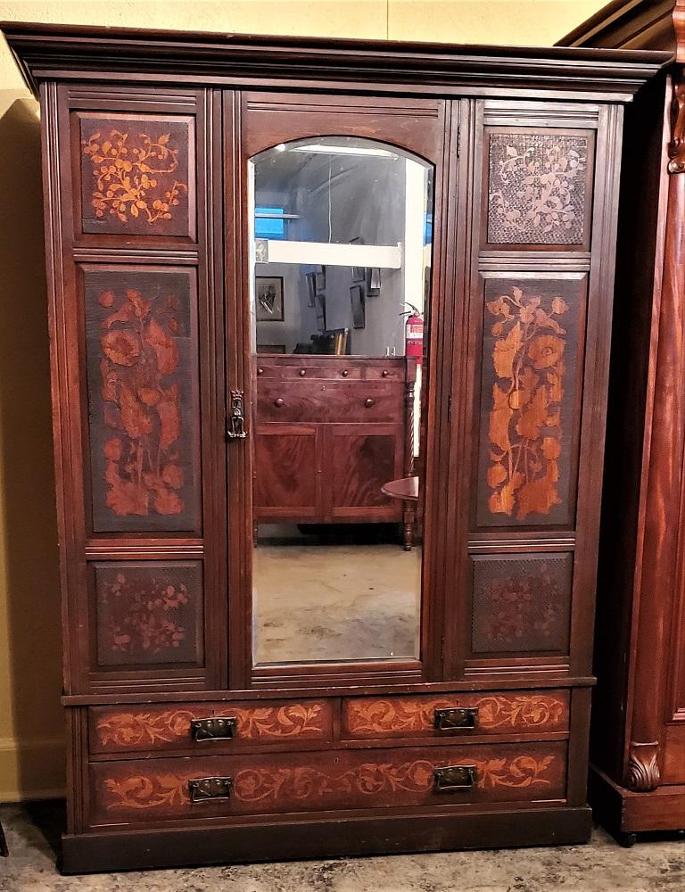 Presenting a rare British Art Nouveau wardrobe from circa 1895.

This is a very unusual and rare wardrobe/armoire.

The main wood used in construction is dark brown walnut.

From a distance, it almost resembles Dutch marquetry work from the
