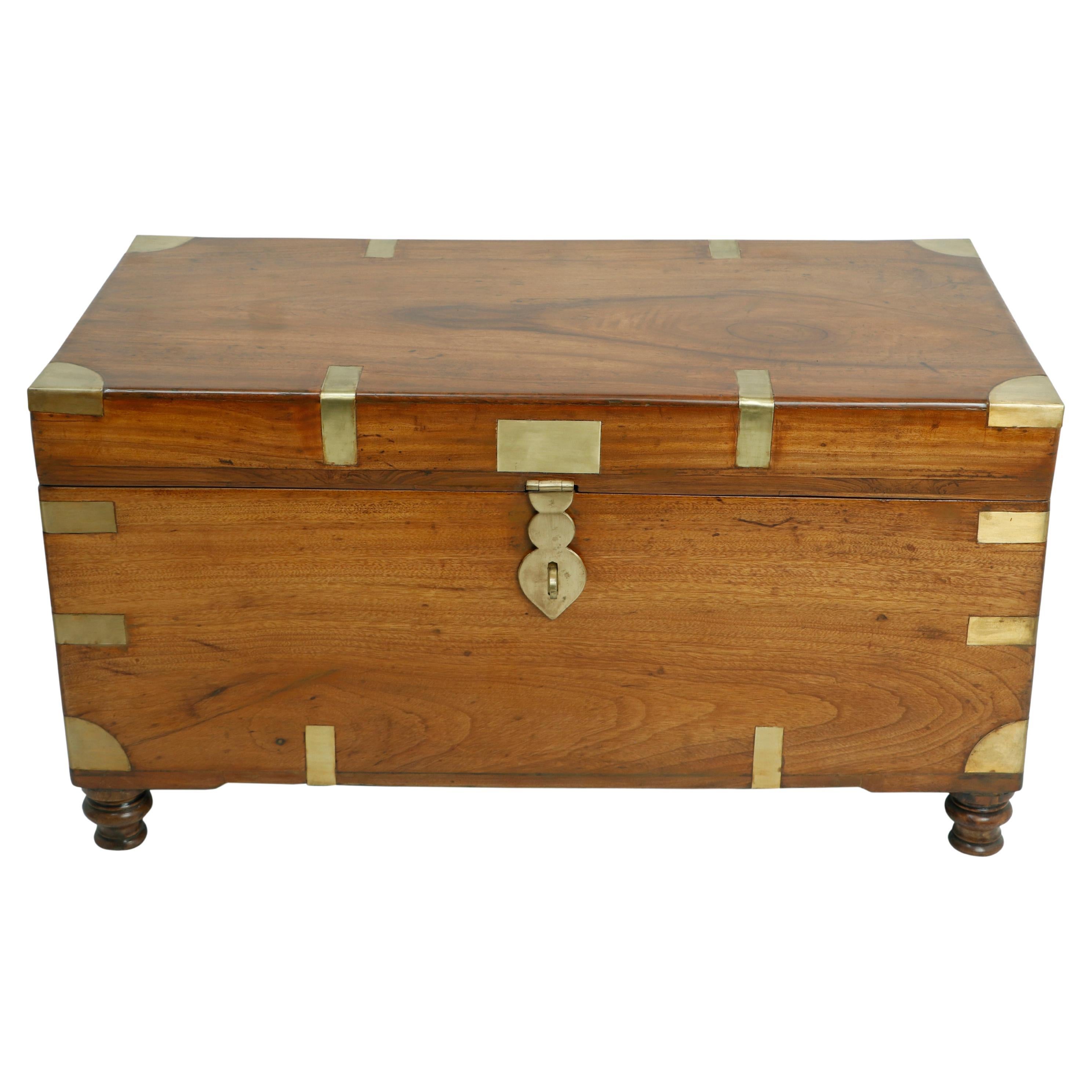 Arcón de campaña británico de principios de 1900 en una rara madera de alcanfor.  Aldaba de latón añadida y esquinas de la correa de latón pulido típicas del género.  Se utilizaba para transportar sedas y telas a Inglaterra.  Utilízala como arcón