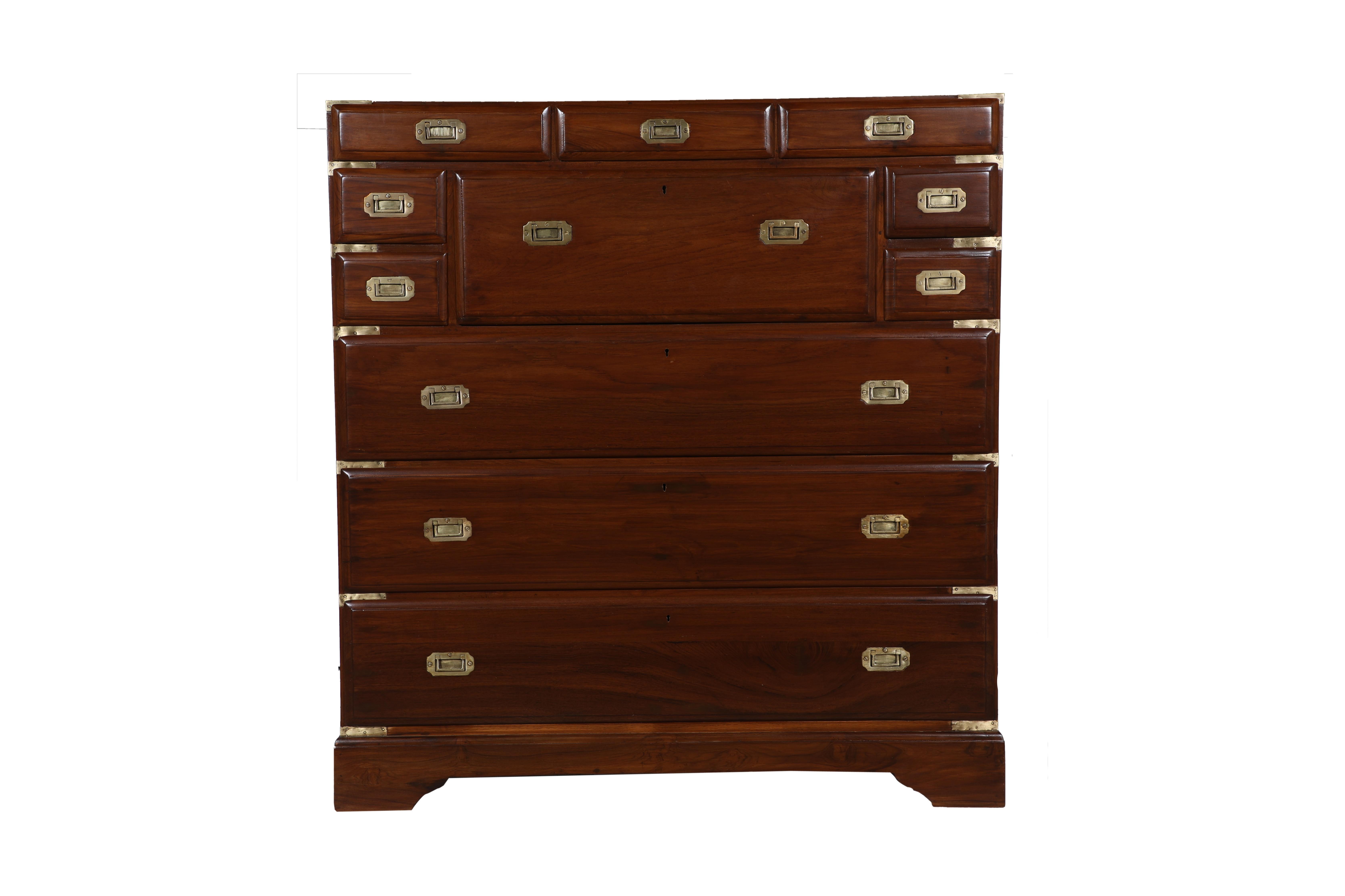 A handsome British Campaign secretary and chest of drawers in teak with brass strap corners and brass flush drawer pulls. It features a center drop down writing desk with a fitted interior. The desk portion pulls forward and sits 14