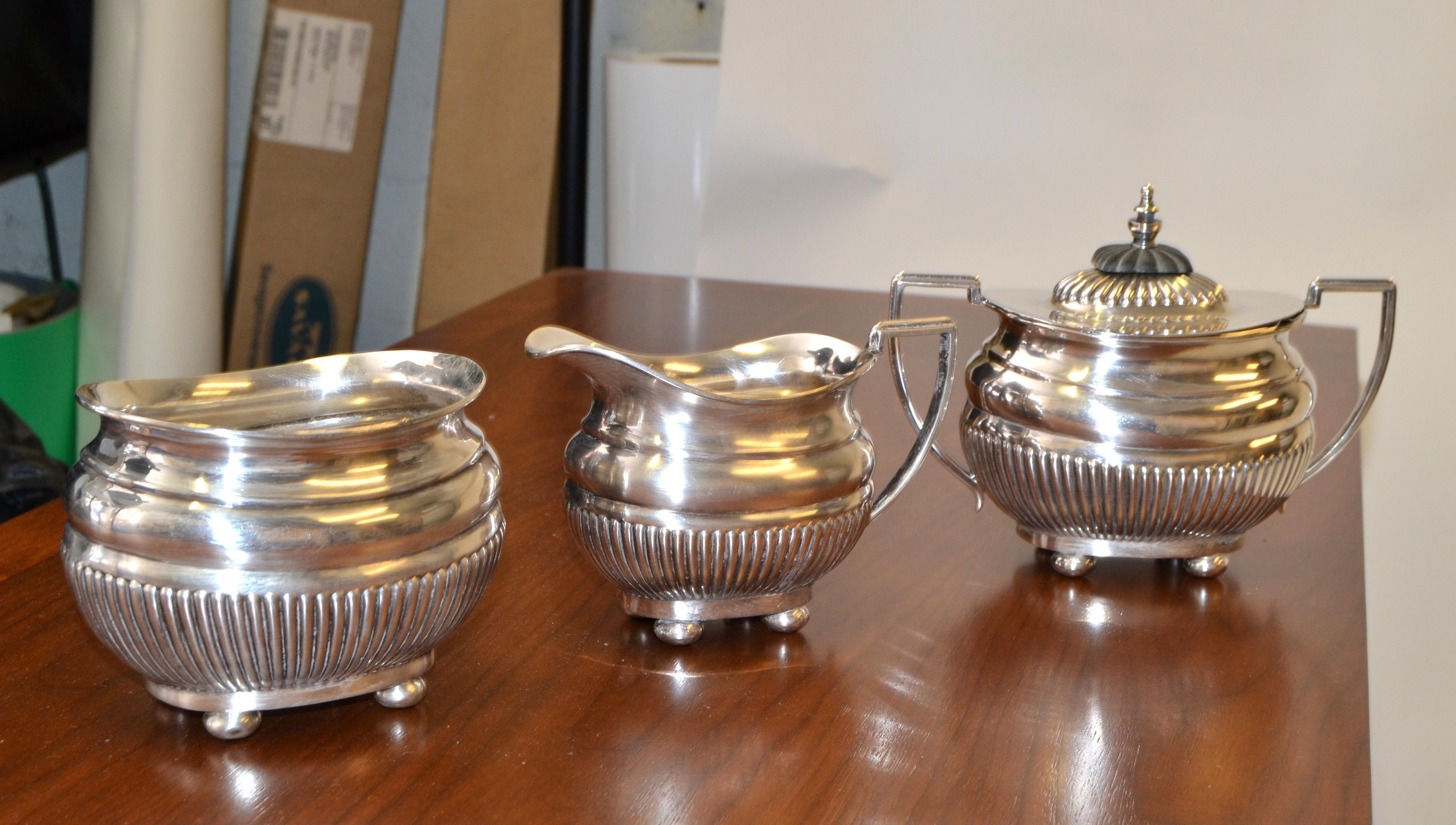 Service à café en argent anglais de 1910 par Cheltenham & Company, Ltd. Sheffield, Angleterre.
Les trois pièces portent les mêmes marques de fabrique sur le fond, ainsi que la marque W A Trademark, Warranted Hard Solder England 69430.
Le sucrier