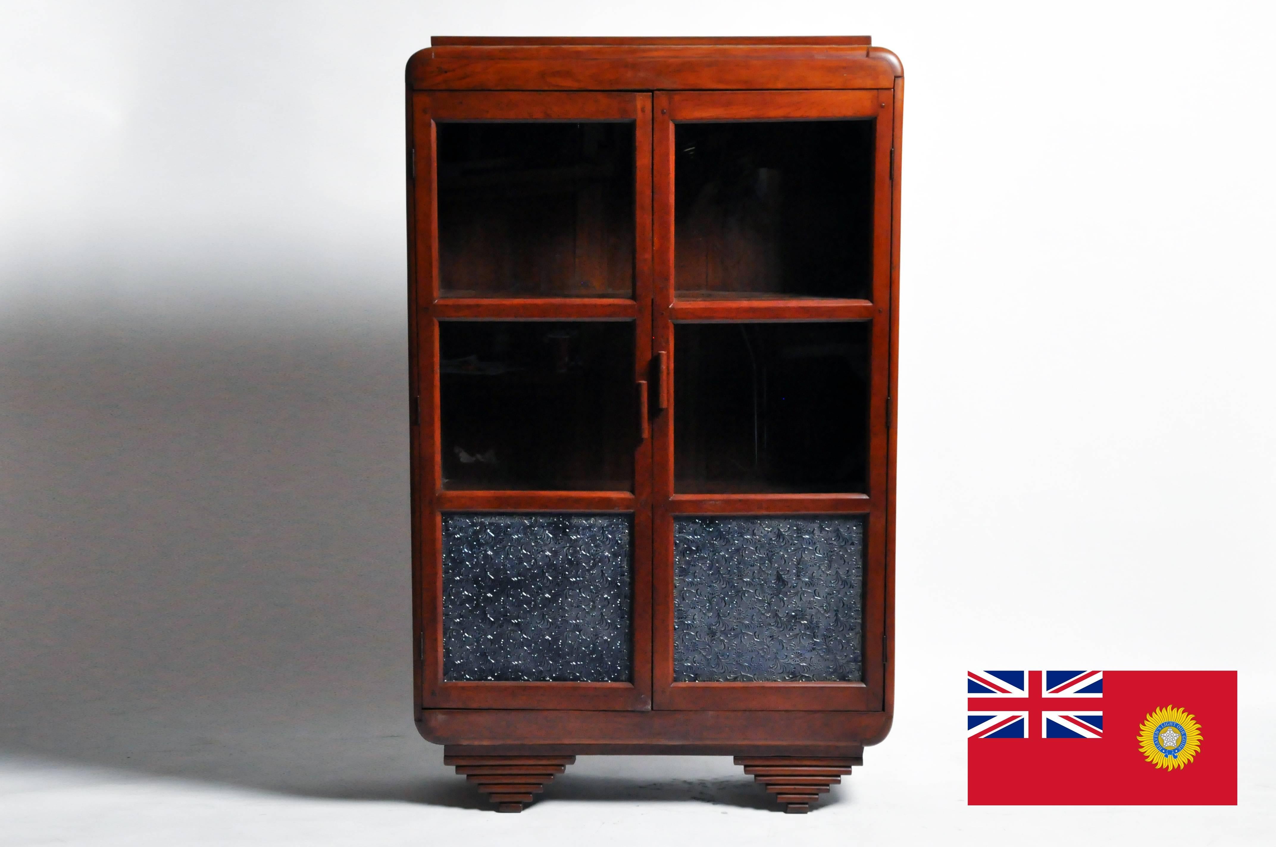 This charming British Colonial Art Deco display cabinet would also make a wonderful hutch. The piece features 2 blue frosted glass and while the beautifully aged patina emits a warm glow. Made from teak wood the piece also has a natural insect