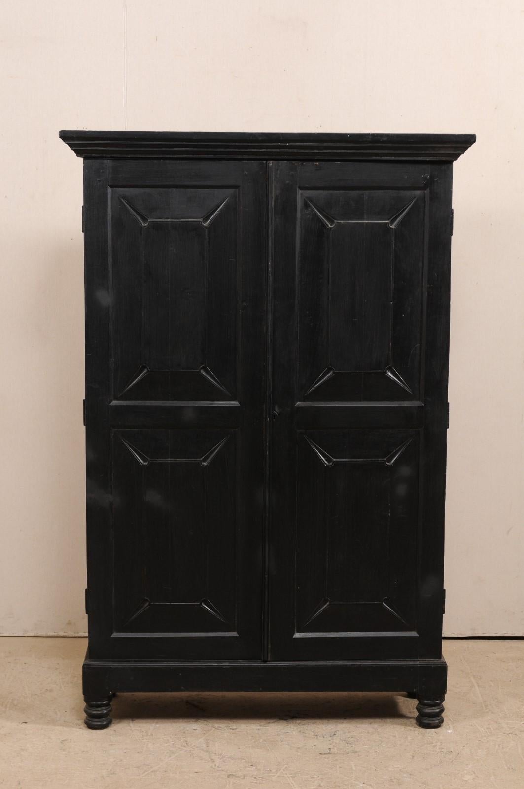 A British Colonial cabinet from the mid-20th century. This vintage cabinet features two decoratively carved raised panel doors, revealing the interior shelving within, framed within a molded cornice at top, and plain skirt at cabinet bottom. It is