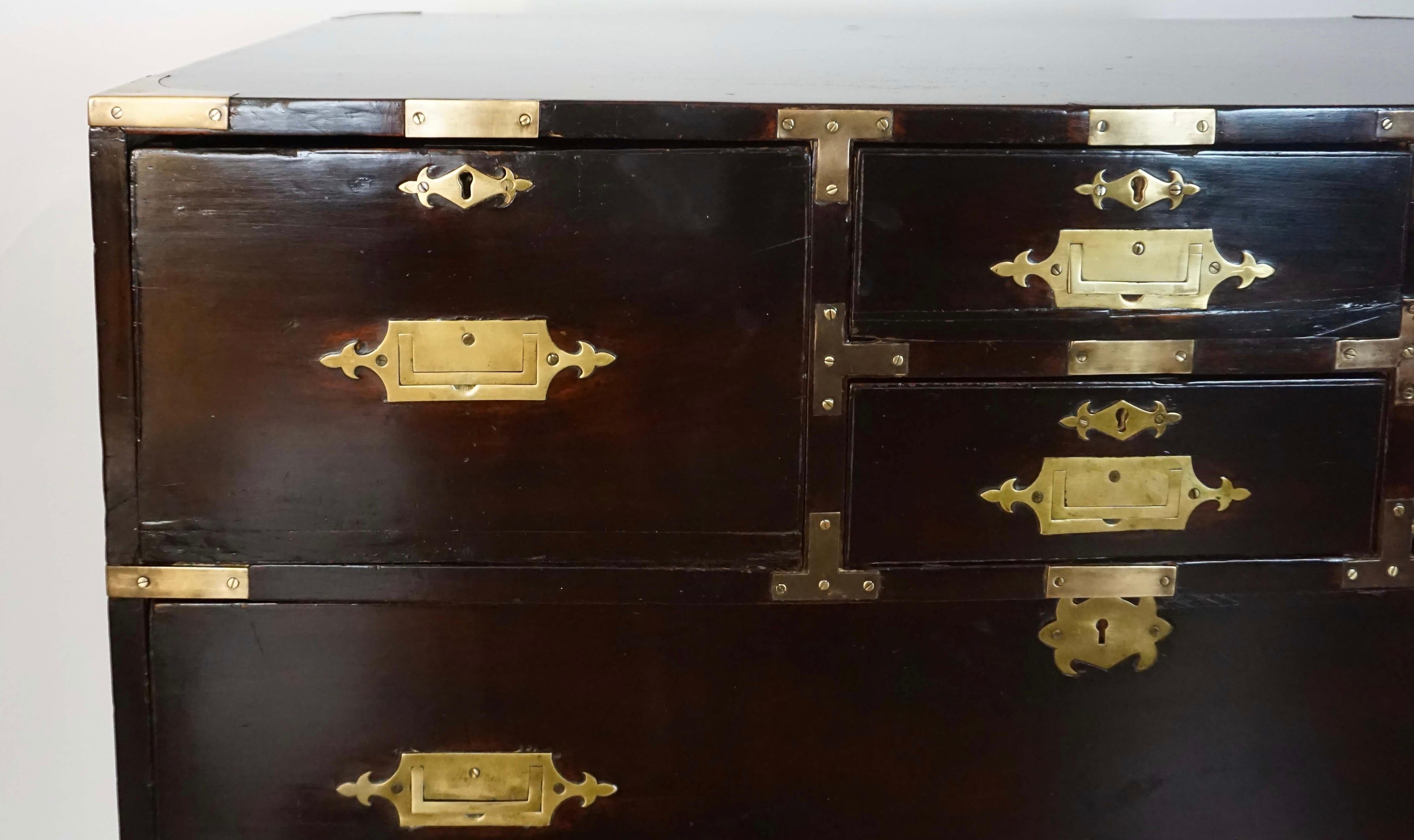 Second quarter 19th century British colonial campaign chest of seven drawers in two parts constructed of solid teak with original ebonized finish and brass hardware atop later platform stand base. A phenomenal example of considerable size and weight.