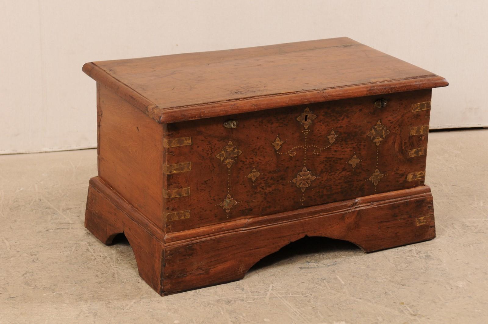 A British Colonial chest, which could function well as a small coffee table, from the early 20th century. This antique British Colonial keep-sake trunk of jack-wood is nicely adorn with a floral motif brass inlay pattern about it's front-facing