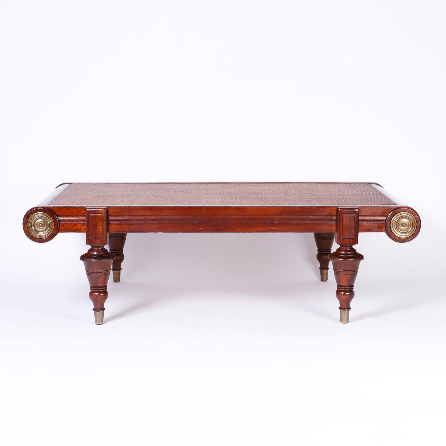 Refined British Colonial coffee table crafted in mahogany with a grass cloth top, Classic form, brass medallions and bold turned legs on brass feet.