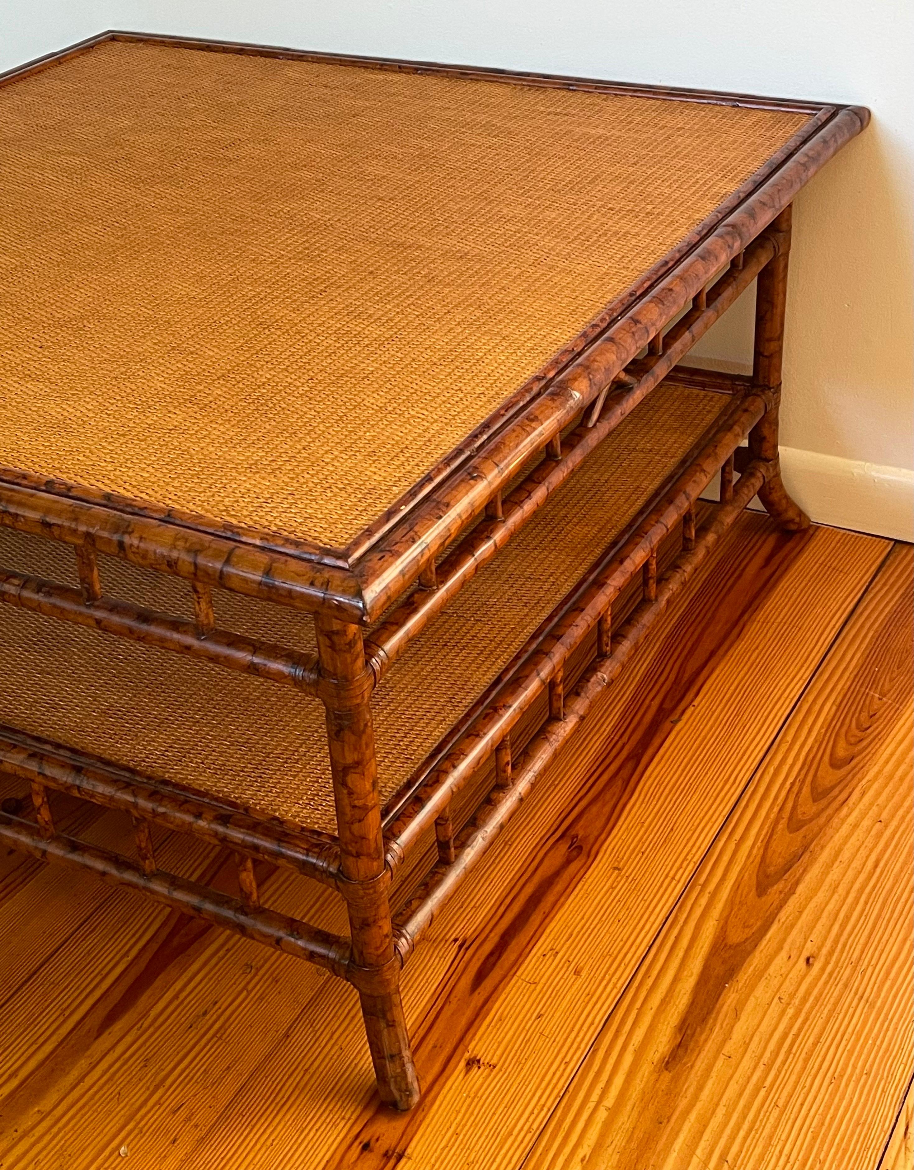 Stunning mid-century British Colonial style coffee table with a faux bamboo frame and two grass cloth tiers over splayed feet, 1980's.