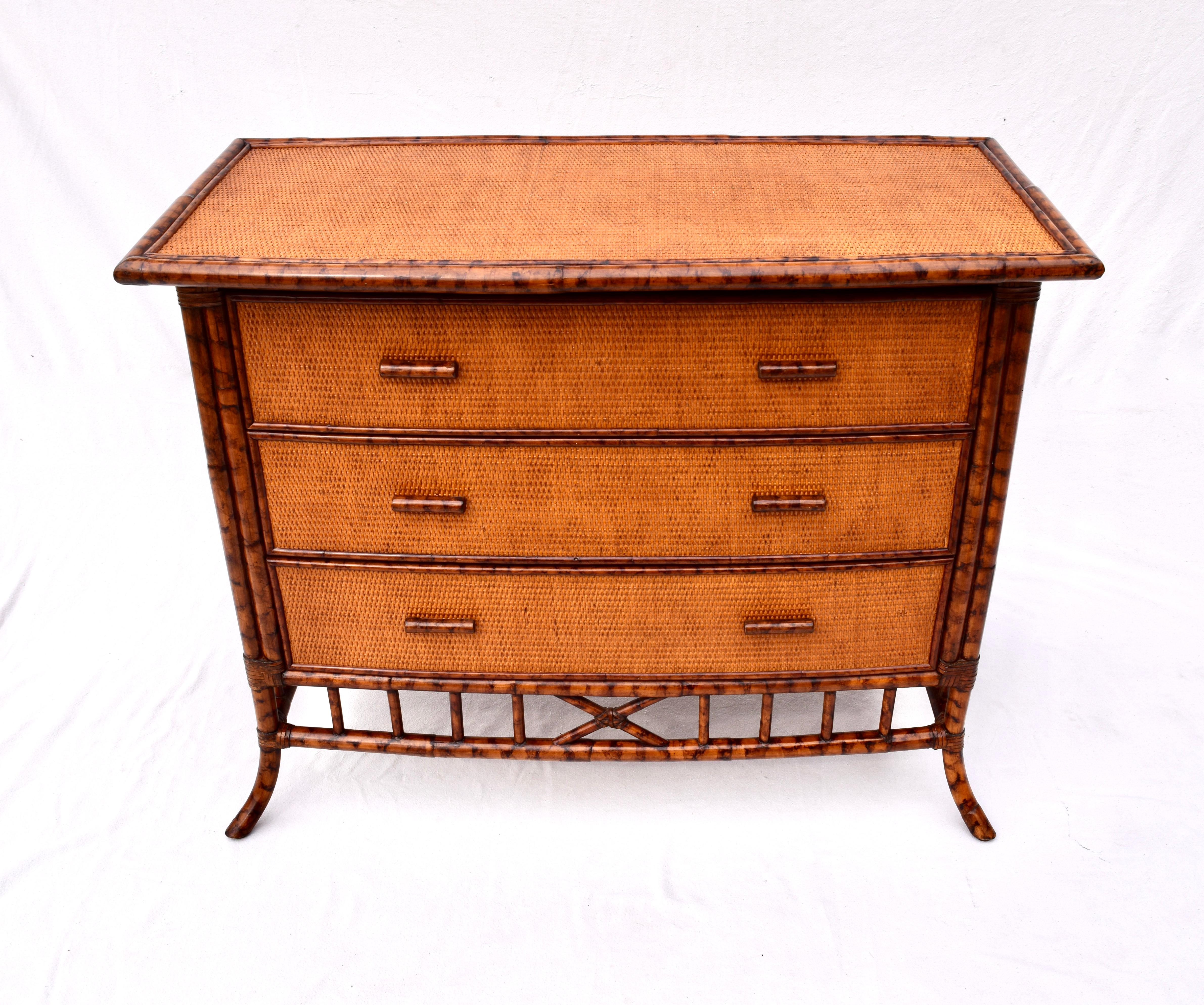 A tortoise or burnt bamboo grass cloth chest of three drawers with old world X-base and splay leg styling after British Colonial furniture of the 19th century. An especially solid chest secured in rawhide leather joinery in rarely used
