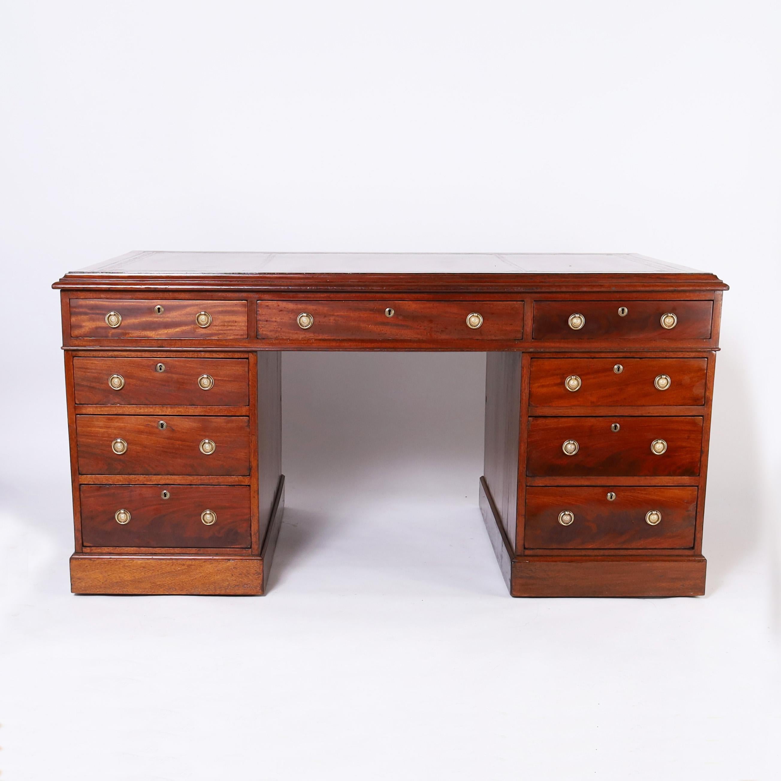 Impressive 19th century British colonial partners desk hand crafted in well grained mahogany with a tooled leather top on a case with three drawers on either side over two pedestals having six drawers on one side and two cabinets on the other, both