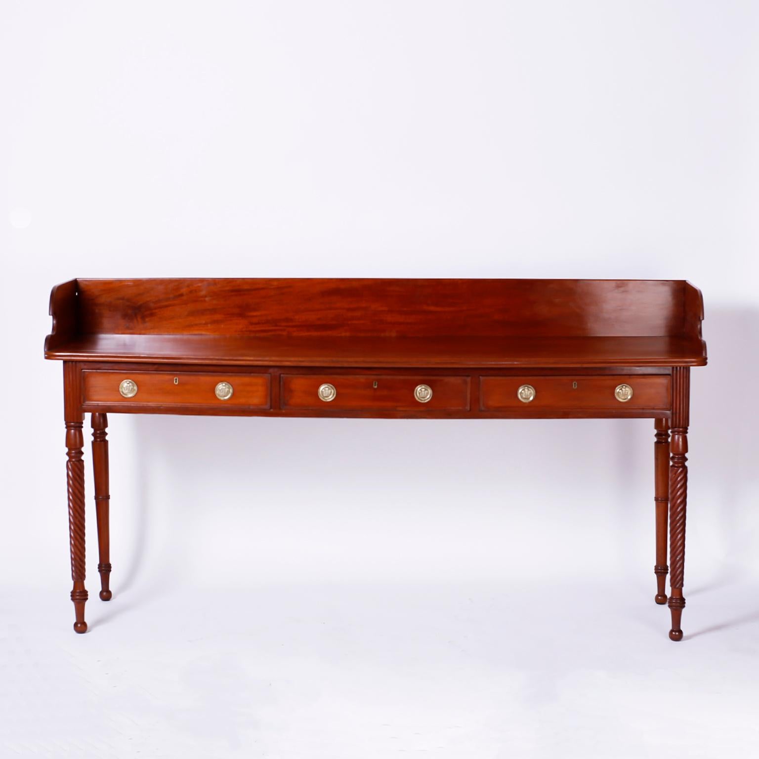 19th century British colonial server with a long lean form featuring handmade construction, a gallery on the top, single plank serving surface, three storage drawers, and elegant turned and rope twisted legs.