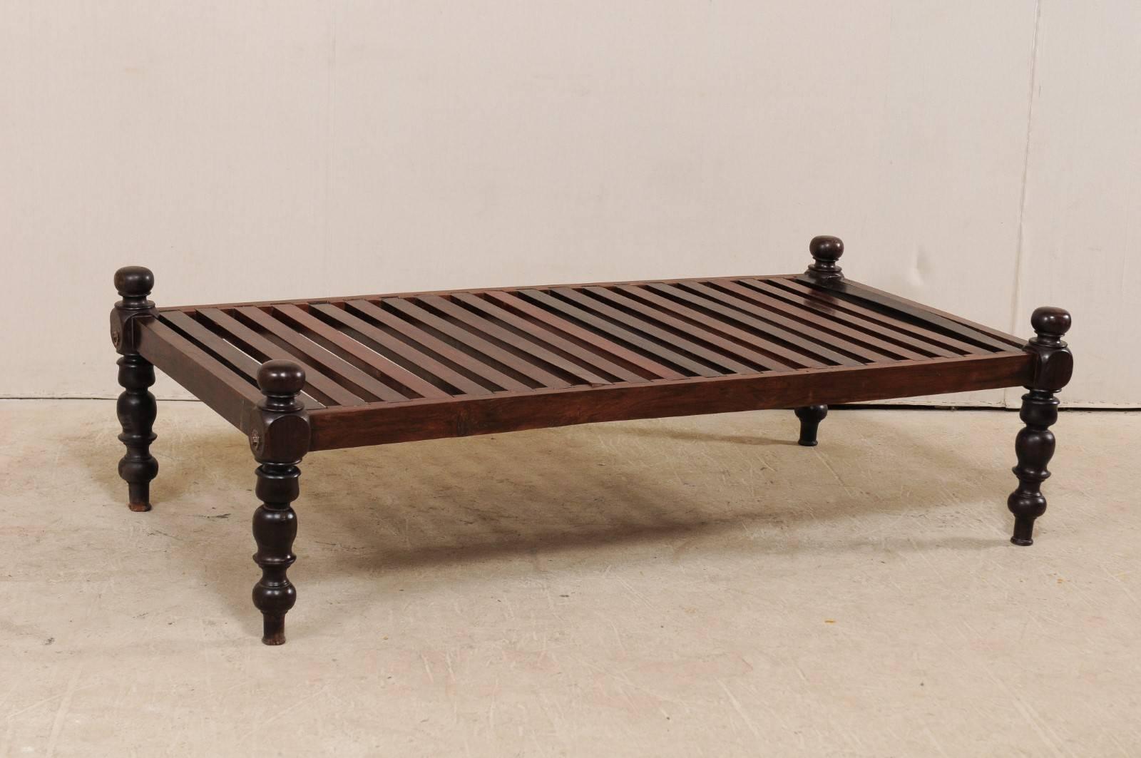 A British Colonial daybed from the mid-20th century. This vintage British Colonial style daybed from India features a sturdy wooden constructed slat bed, and four nicely turned legs, which rise slightly giving this bench low profile or open sides.