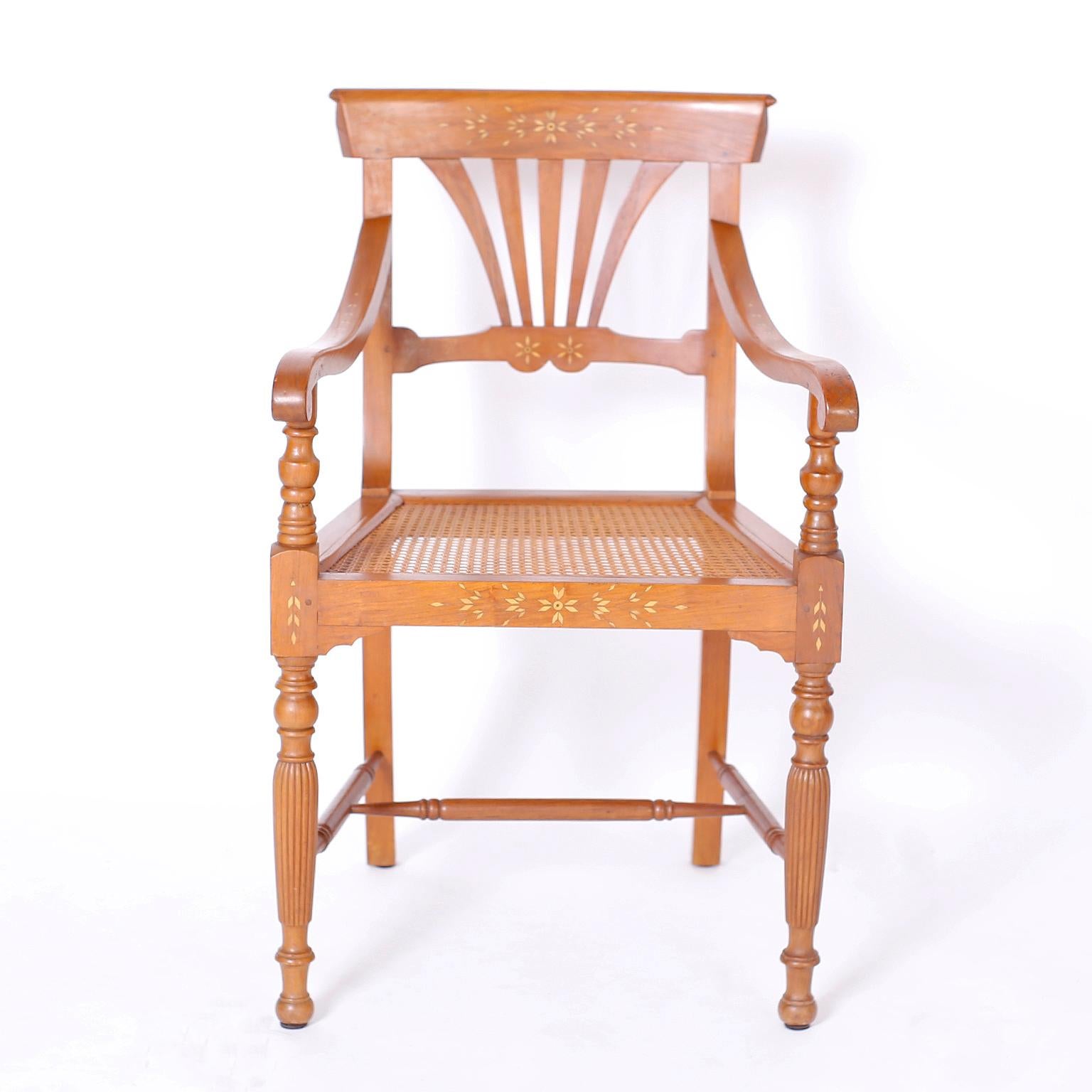 19th century armchair hand crafted in mahogany in the Philippines and featuring pegged construction, floral bone inlays, caned seat, graceful arms, turned and beaded front legs and an overall elegant form.