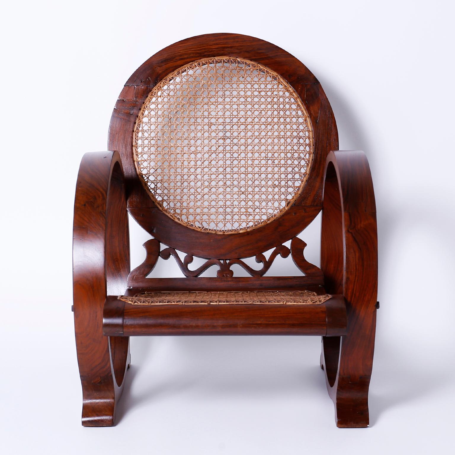 Stand out West Indies British Colonial armchaircrafted in Caribbean rosewood with a distinctive Art Deco form, having round bentwood sides, hand caned seat and back, and a handmade pegged construction. Chairs of this genre were made in Jamaica.