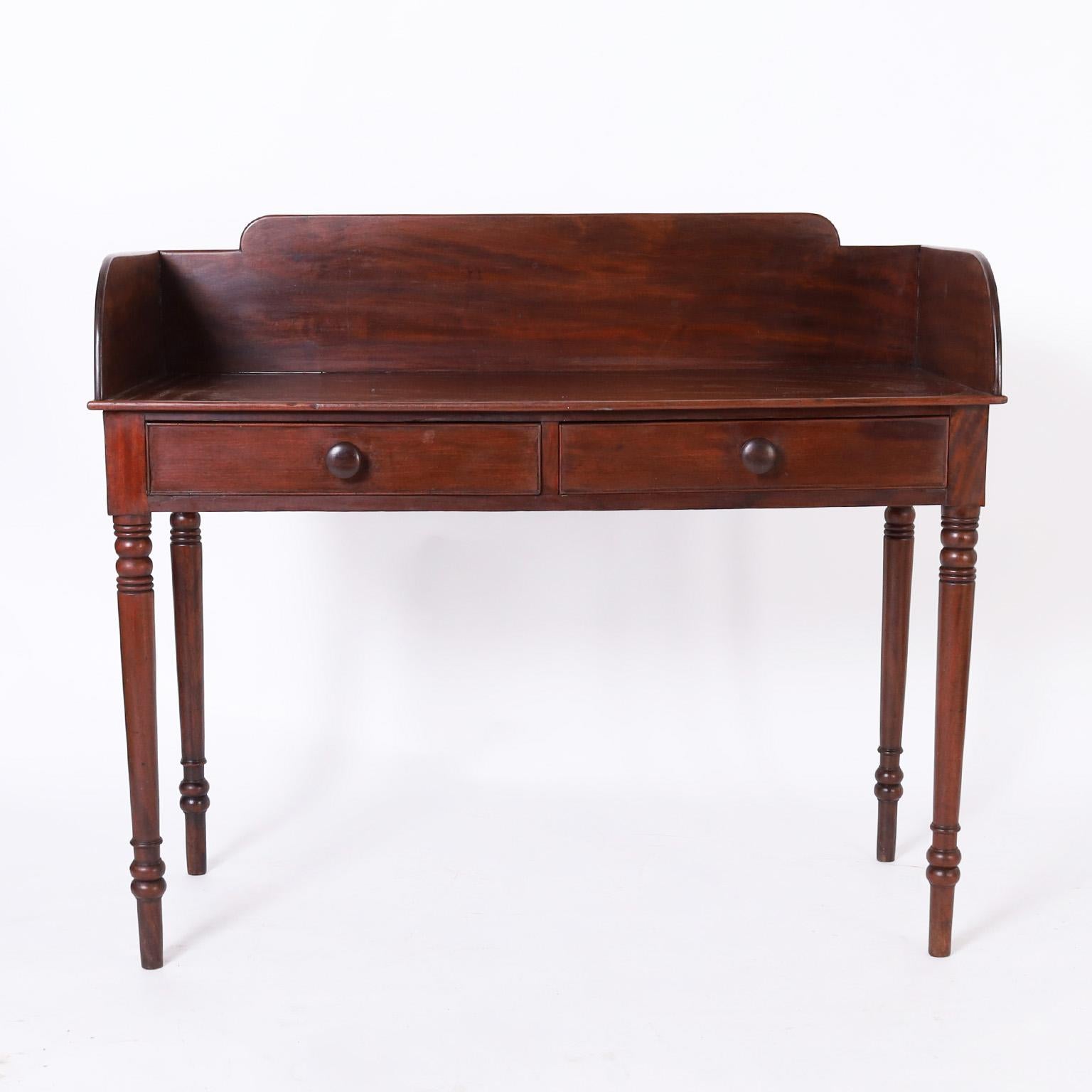 Rare and remarkable early 19th century server or bar handcrafted in mahogany with a dark lush finish having a gallery around the top, two drawers, and long elegant turned legs.