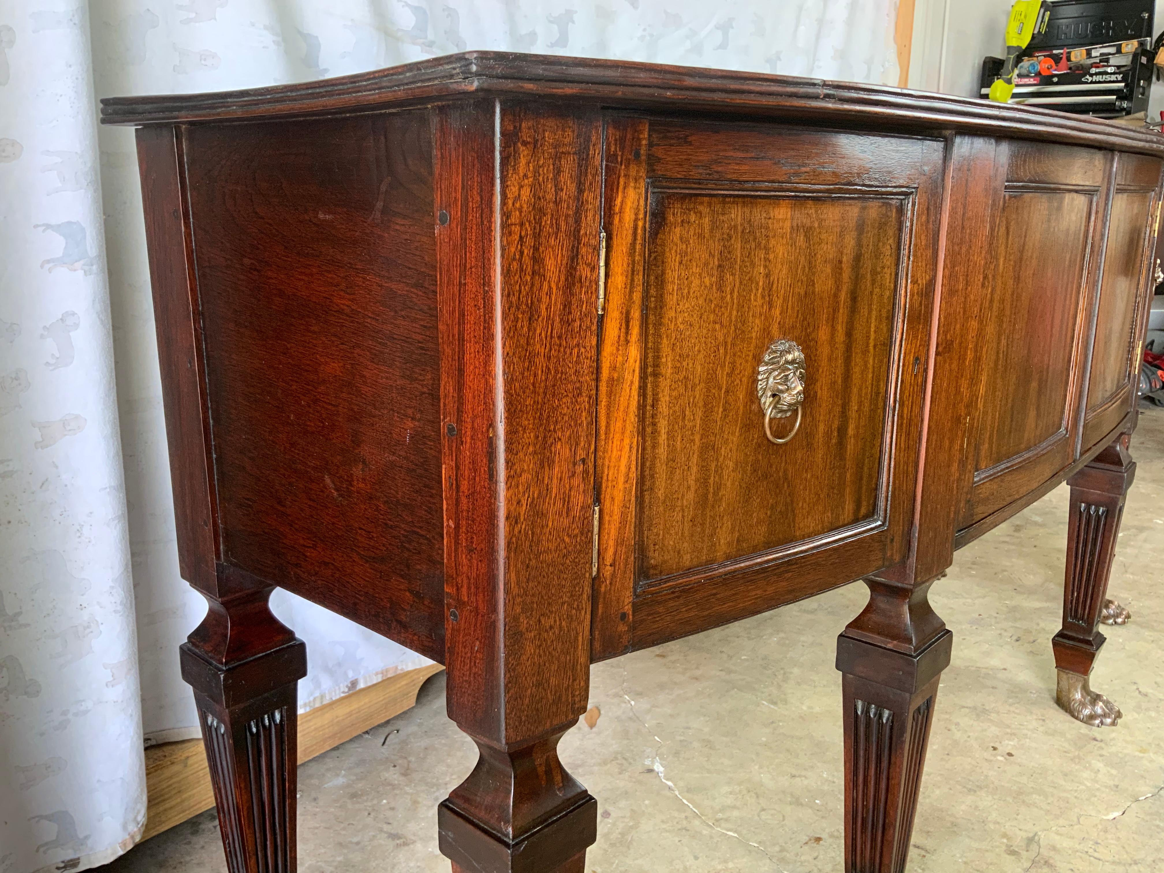 British Colonial Mahogany and Teak sideboard with very nicely carved fluted tapered legs and brass hairy paw feet. 
Attributed to the British West Indies colonies sometime around the mid to late 1800’s, these colonial pieces were commonly made in