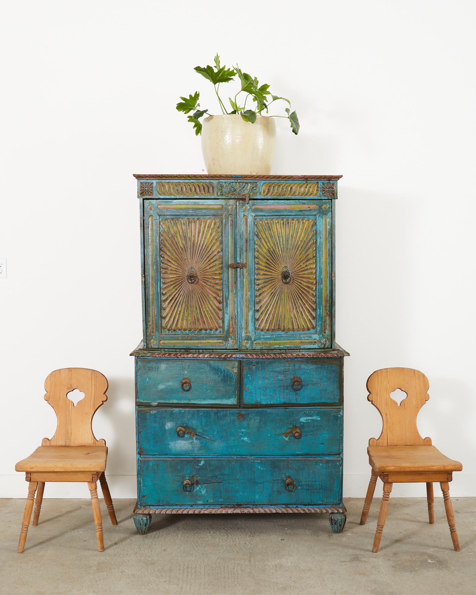 Fantastic Anglo-Indian 2-part linen press cabinet or dresser made in the British colonial style. The cabinet features two large front doors with a dramatic sunburst relief carving that opens to a large storage area. The doors are painted in a