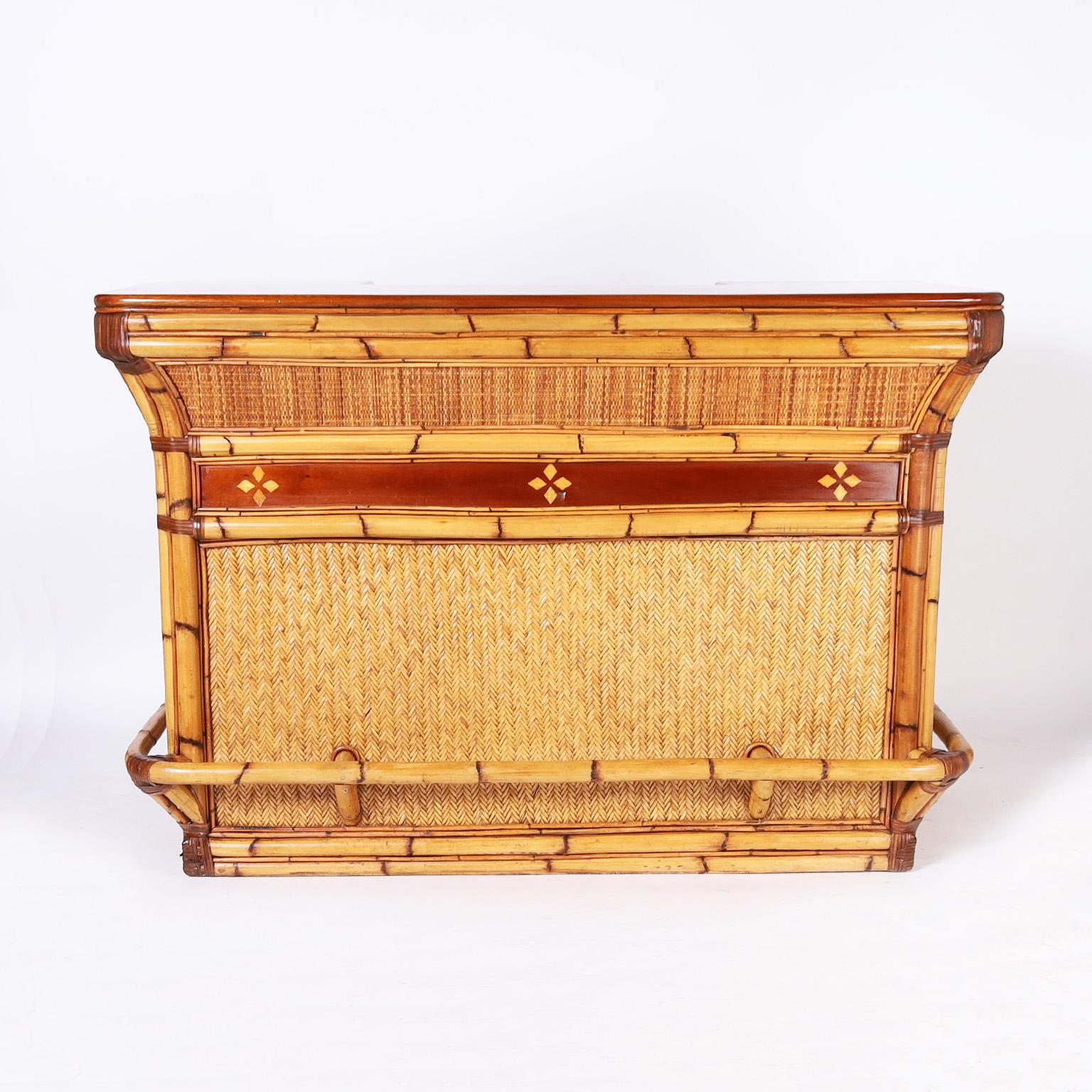 Vintage bar crafted in bamboo and rattan with a mahogany top and side panels and herringbone grasscloth, French polished in the traditional old world manner. The back service area has plenty of storage and workspace with shelves, cabinets, and a