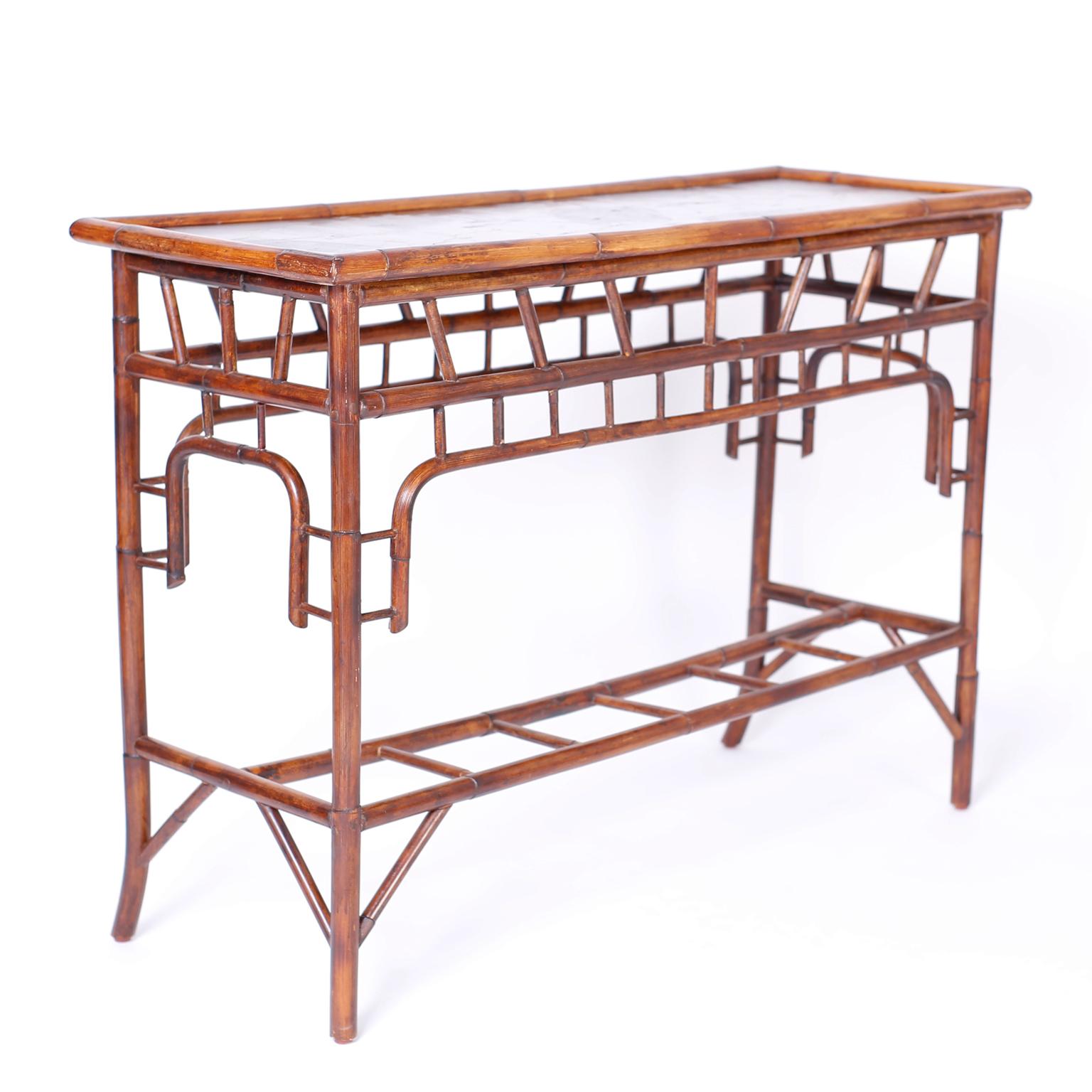 Modern British Colonial Asian influenced console table with hand painted leaves on the top under a textured lacquer finish. The bamboo base has Asian influences and splayed front legs.