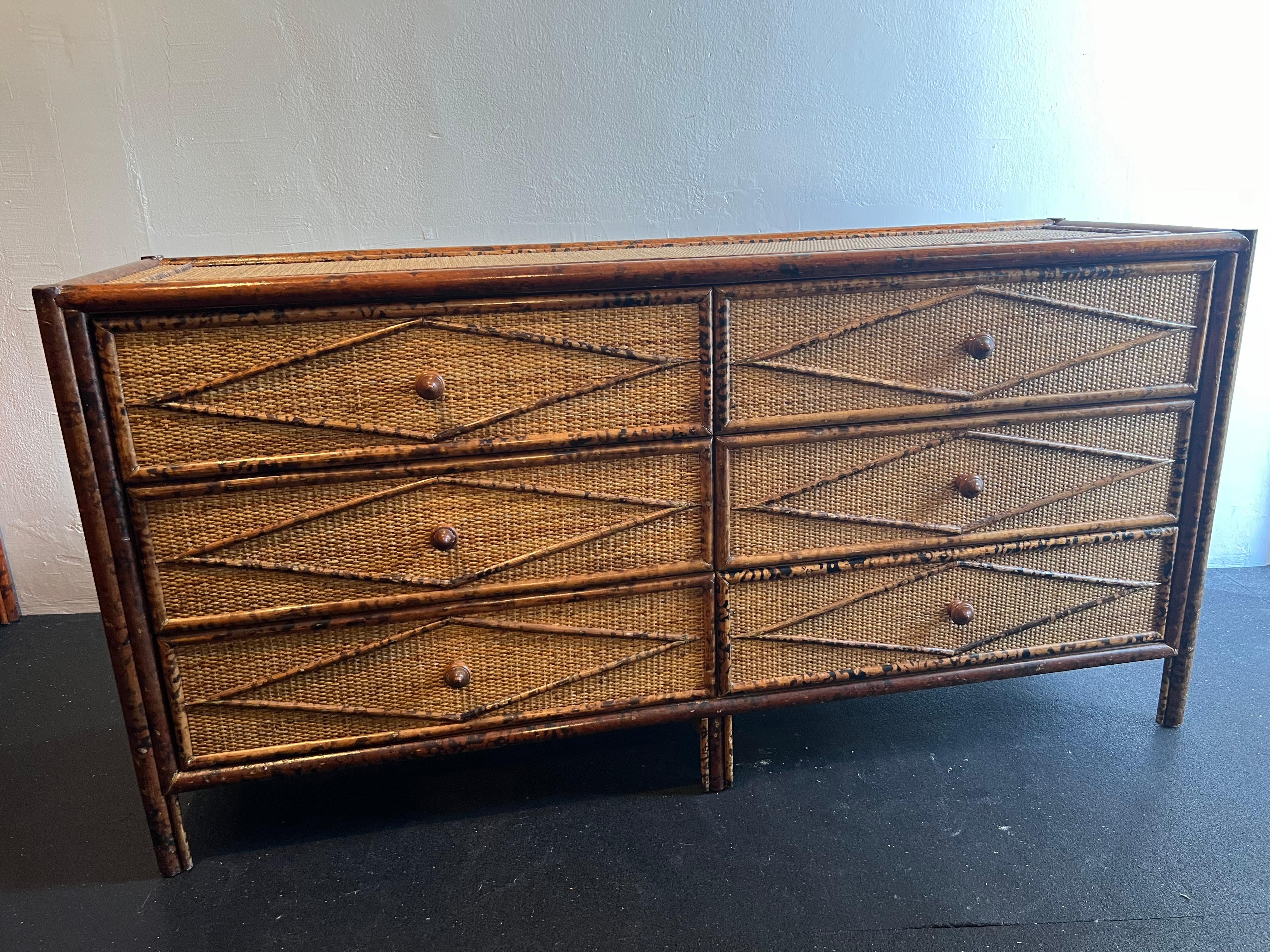 British colonial style burnt bamboo and cane dresser. Wear to finish of cane and bamboo  (please refer to photos). Additional photos available upon request. 

Would work well in a variety of interiors such as modern, mid century modern, Hollywood